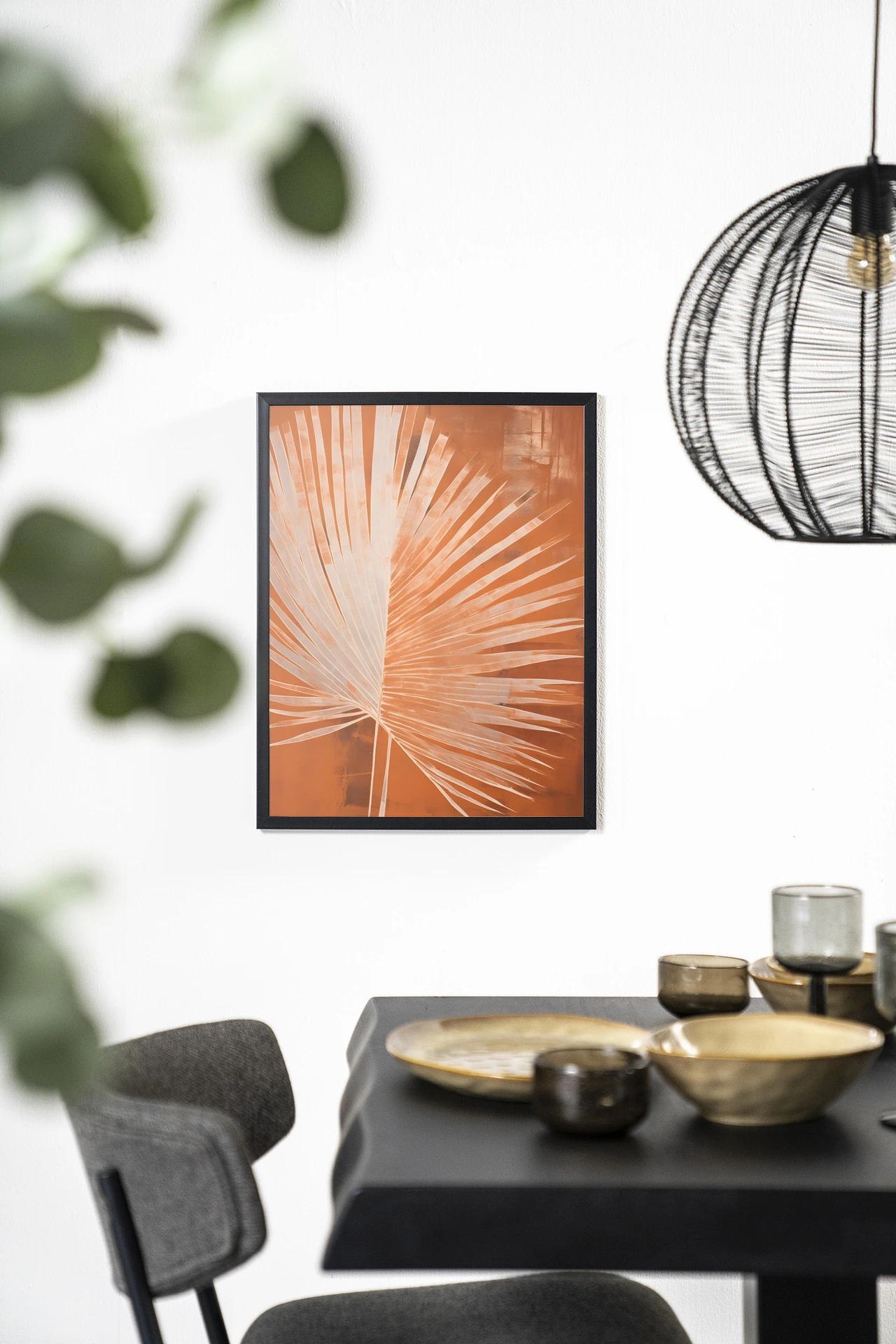 Wandkleed Rusty Palm - Urban Cotton hangend aan een witte muur boven een zwarte tafel