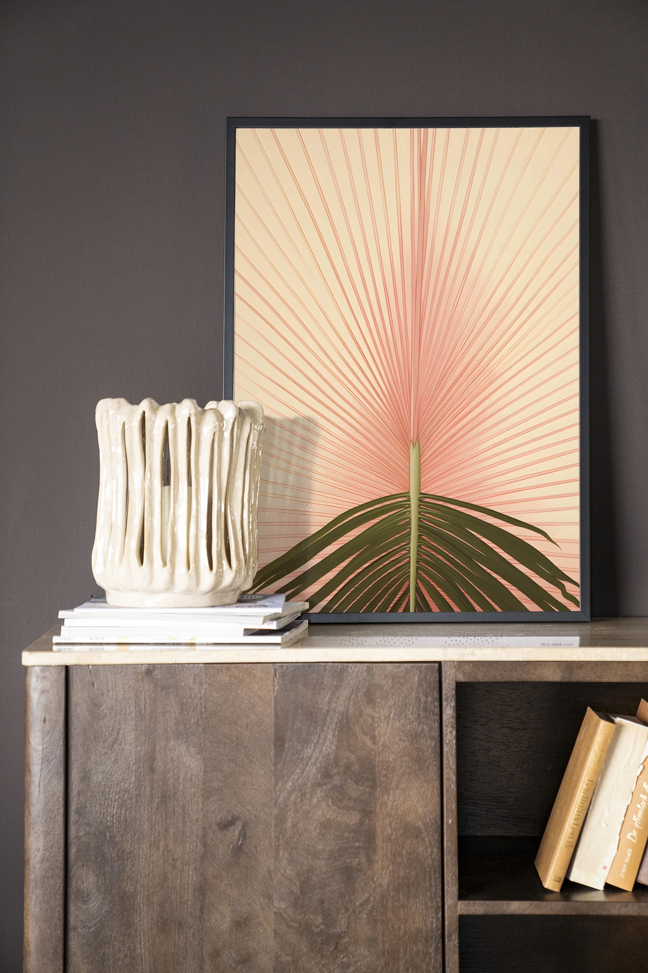 De Art print Palma - Urban Cotton staat op een houten dressoir met een vaas en boeken ernaast