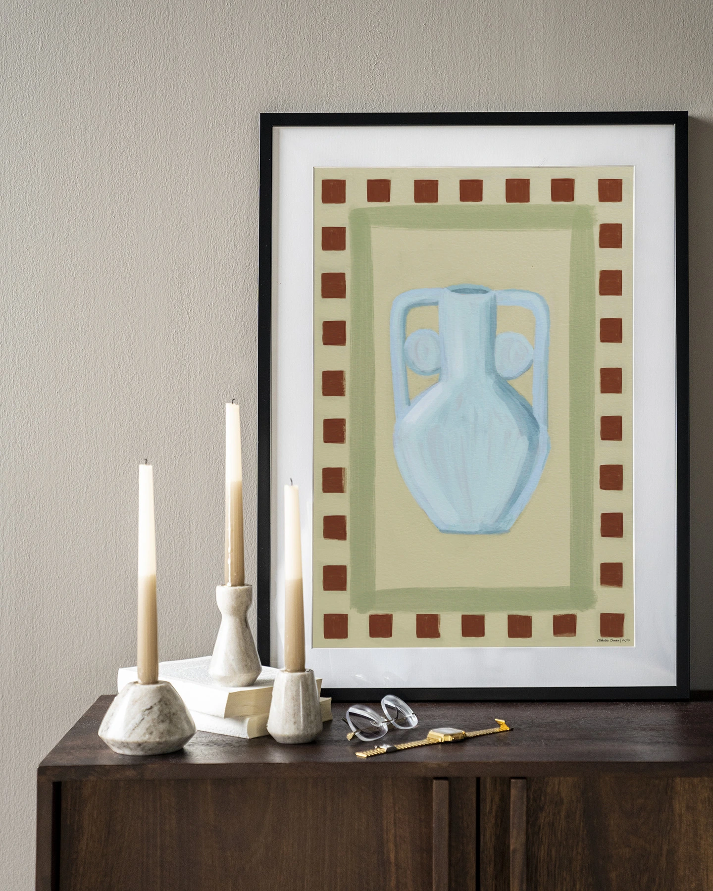 Wandkleed Eclectic Series 1 - Urban Cotton hangend boven een houten dressoir met kaarsen en bril
