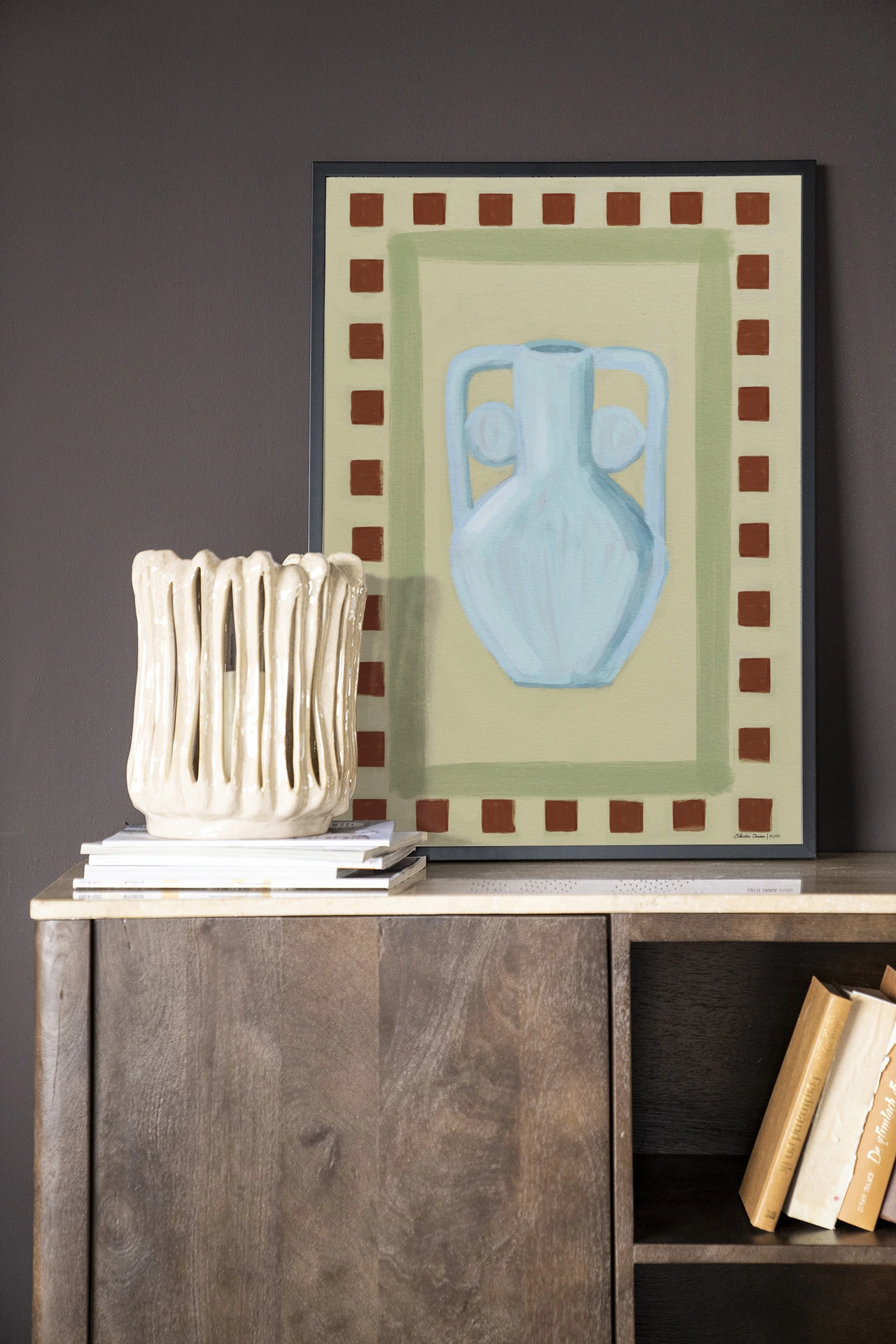 Wandkleed Eclectic Series 1 - Urban Cotton in een lijst, staand op een houten dressoir met een vaas ernaast