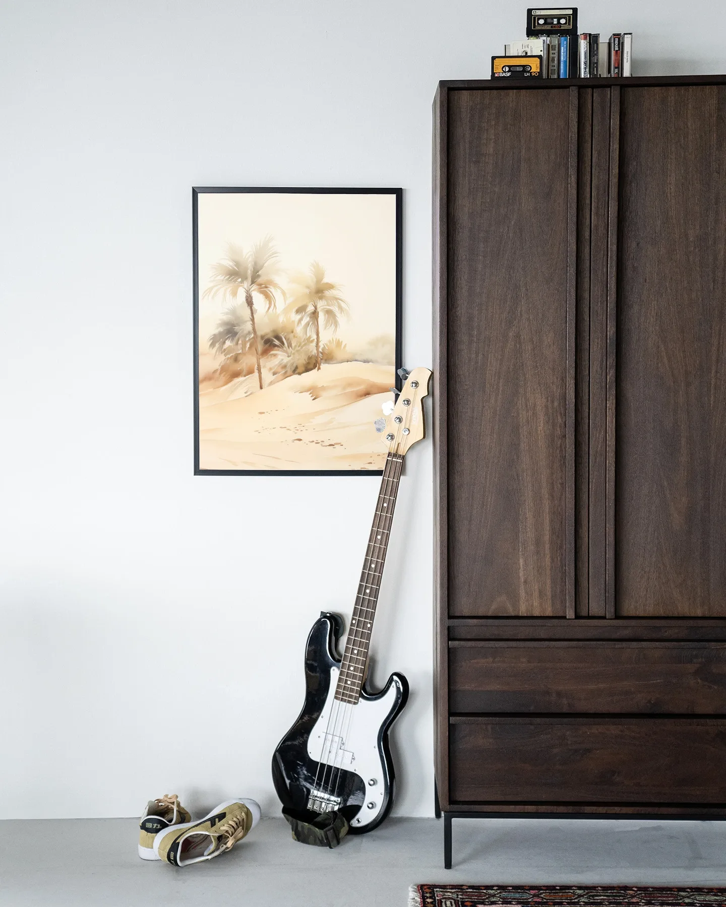 Wandkleed Palm Dust - Urban Cotton hangend aan een witte muur, met een basgitaar en schoenen ernaast