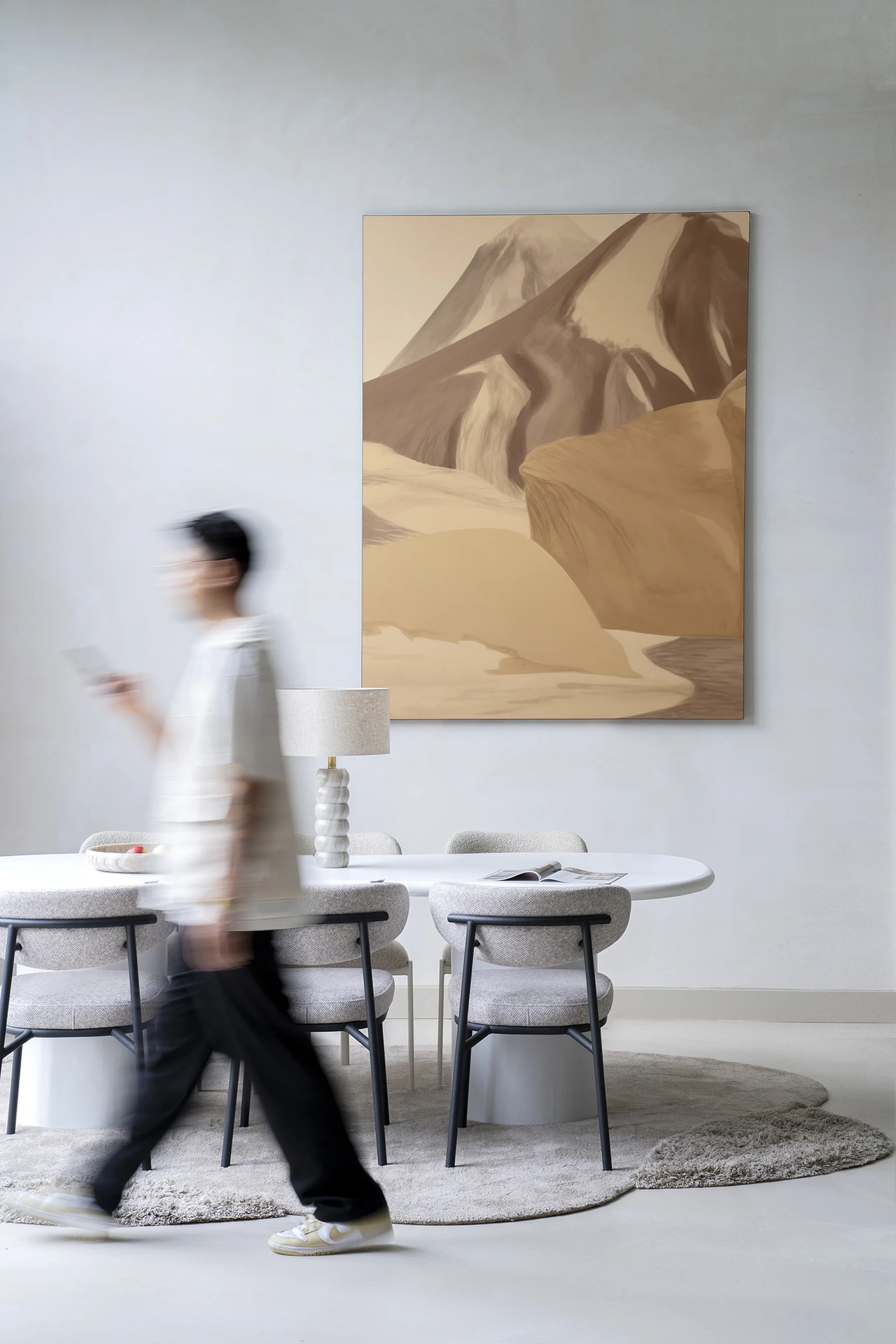 Ein Mann geht am Wandteppich Rocky Mountain - Urban Cotton vorbei, der an einer hellen Wand hängt