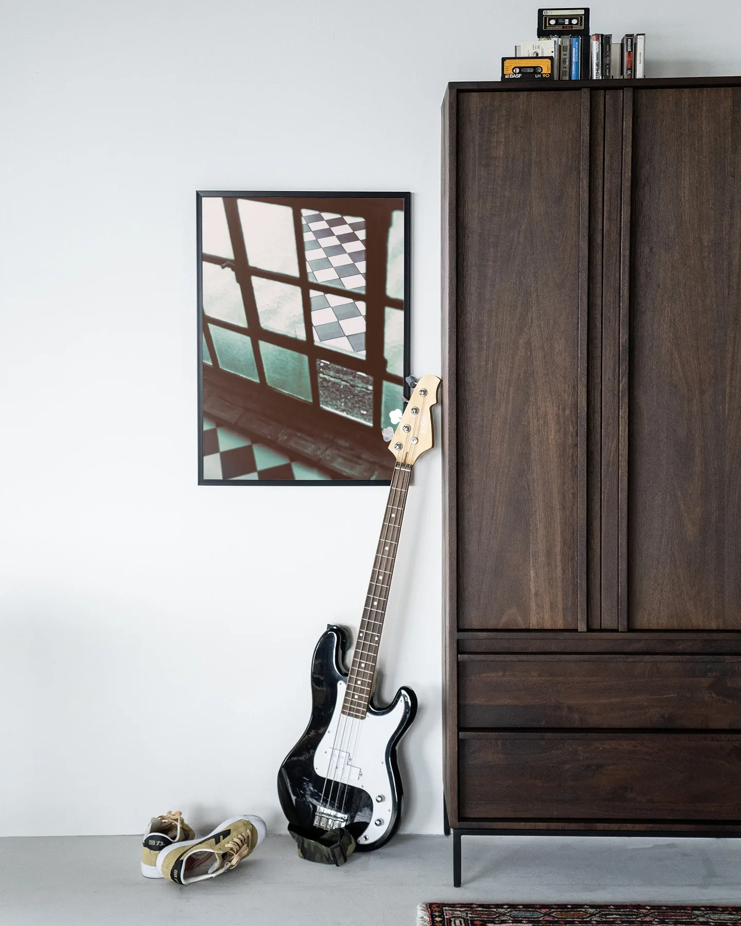Wandkleed No Squaring @ My Door - Urban Cotton hangt aan een witte muur naast een donkerbruine kast met een gitaar ervoor