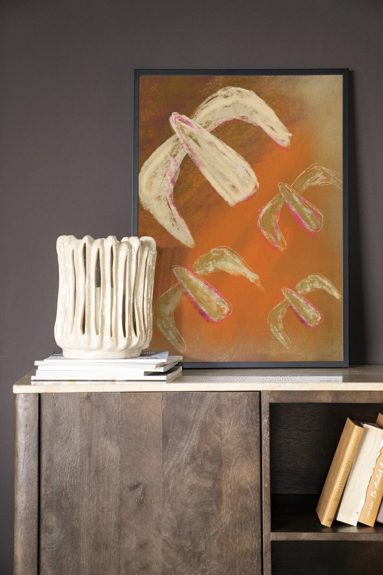 Wandkleed Bird Rise - Urban Cotton hangend boven een houten dressoir met een vaas en boeken