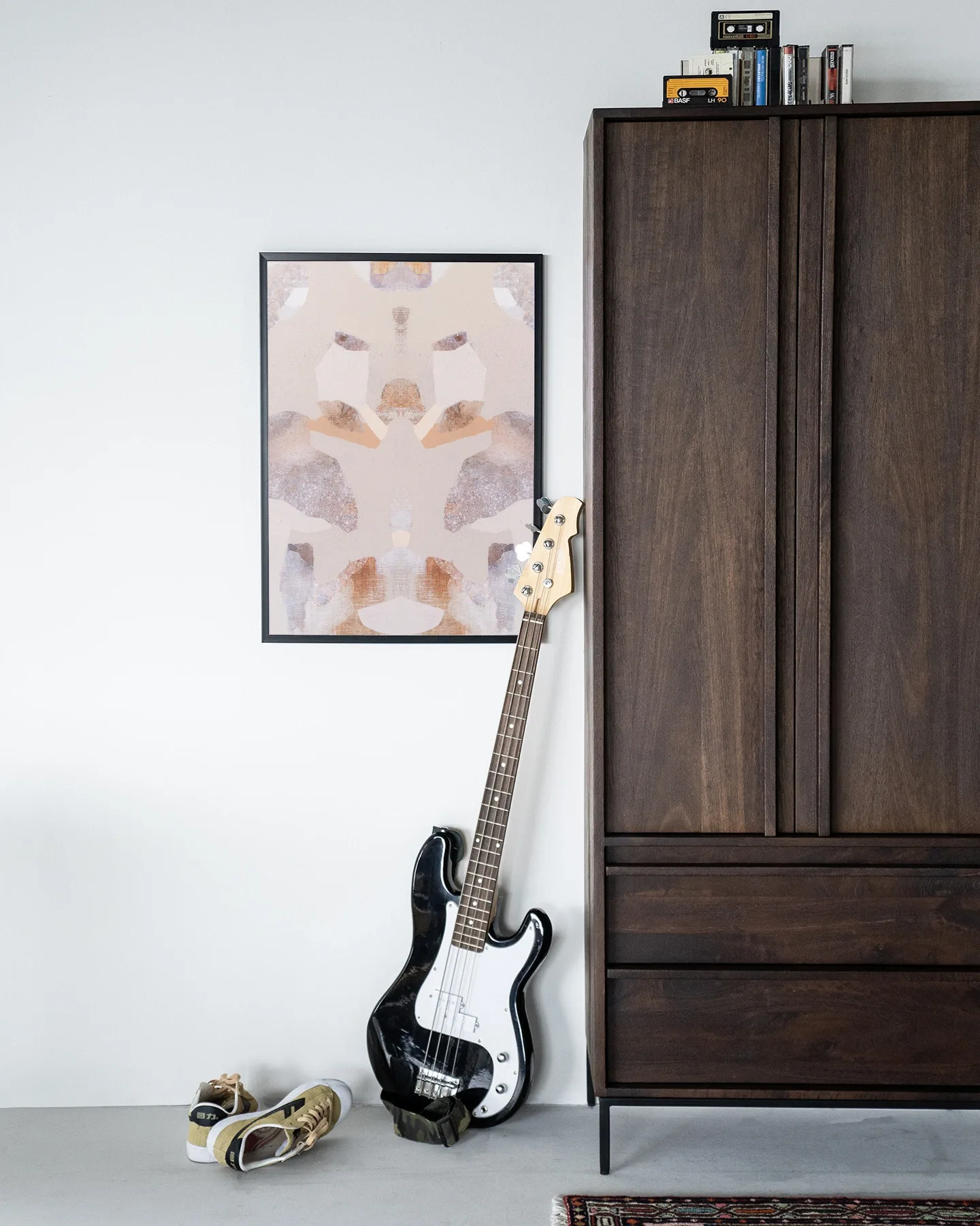 Wandkleed Sand Fox - Urban Cotton hangend aan een witte muur, met een basgitaar en schoenen eronder