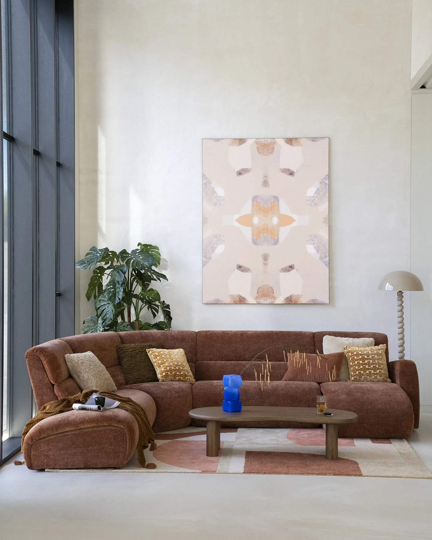 Wandkleed Mountain Lion - Urban Cotton hangend boven een bruine hoekbank in een lichte woonkamer