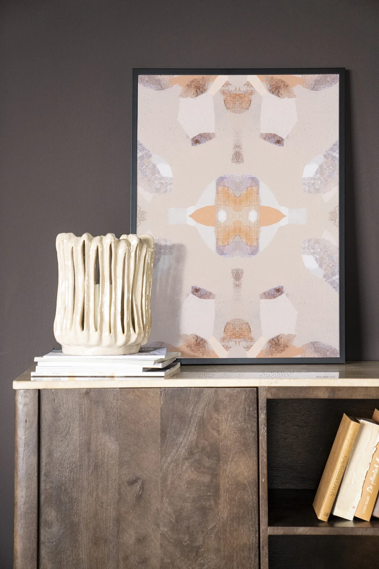 Wandkleed Mountain Lion - Urban Cotton in een lijst, staand op een houten dressoir met boeken
