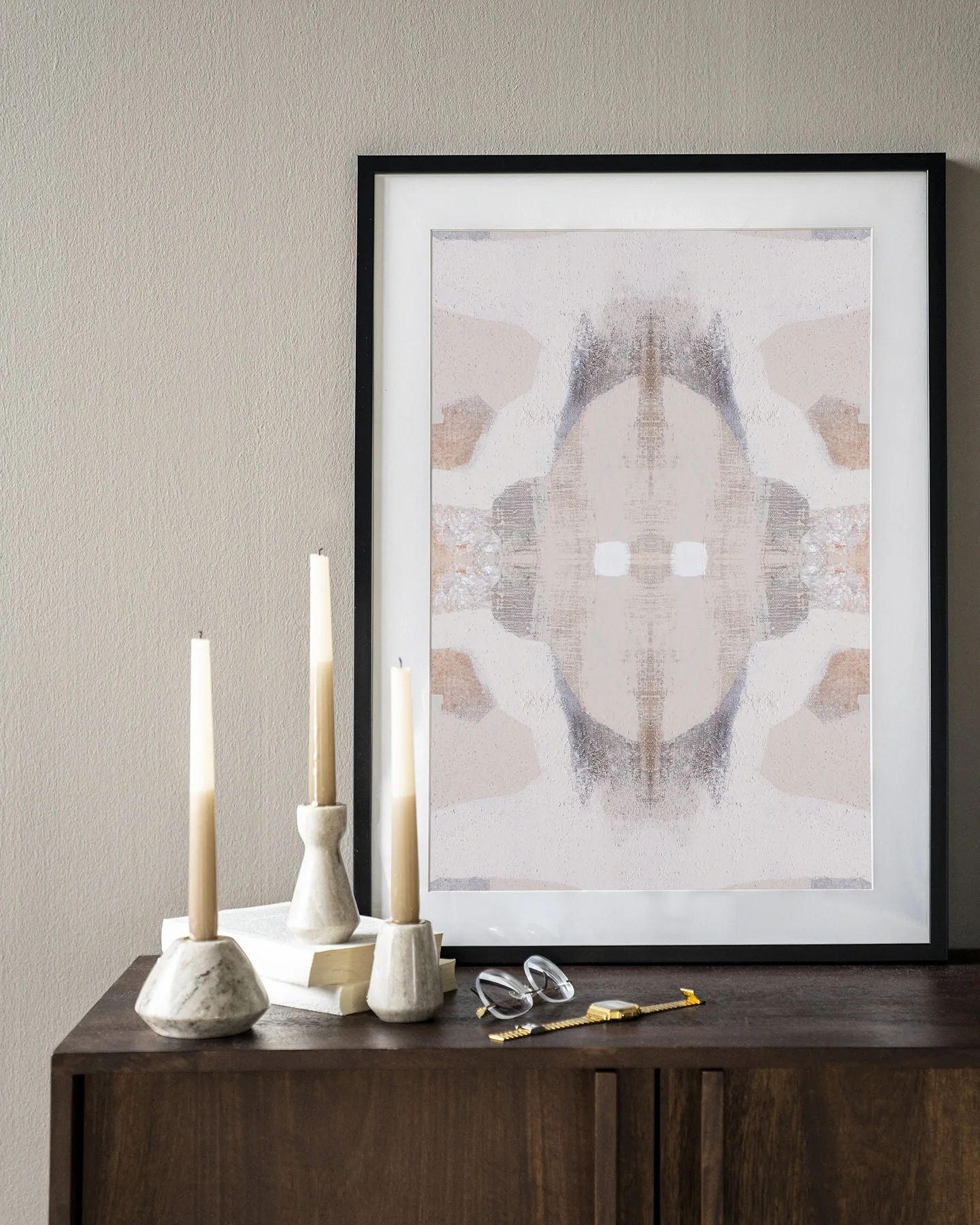 Wandkleed Chiru Antelope van Urban Cotton in een zwarte lijst, staand op een donkerhouten dressoir met kaarsen en boeken