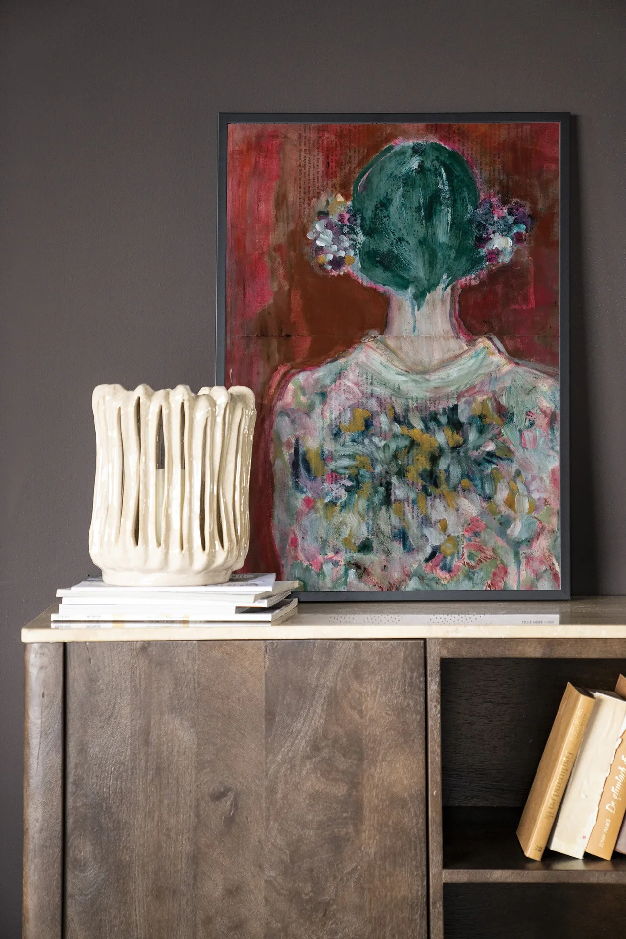Wandkleed Red Velvet - Urban Cotton in een lijst, staand op een houten dressoir met een witte vaas en boeken