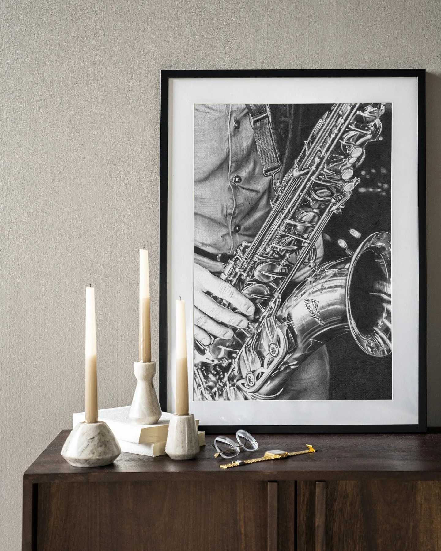 Wandkleed The man with the sax - Urban Cotton hangend boven een houten dressoir met boeken en kaarsen