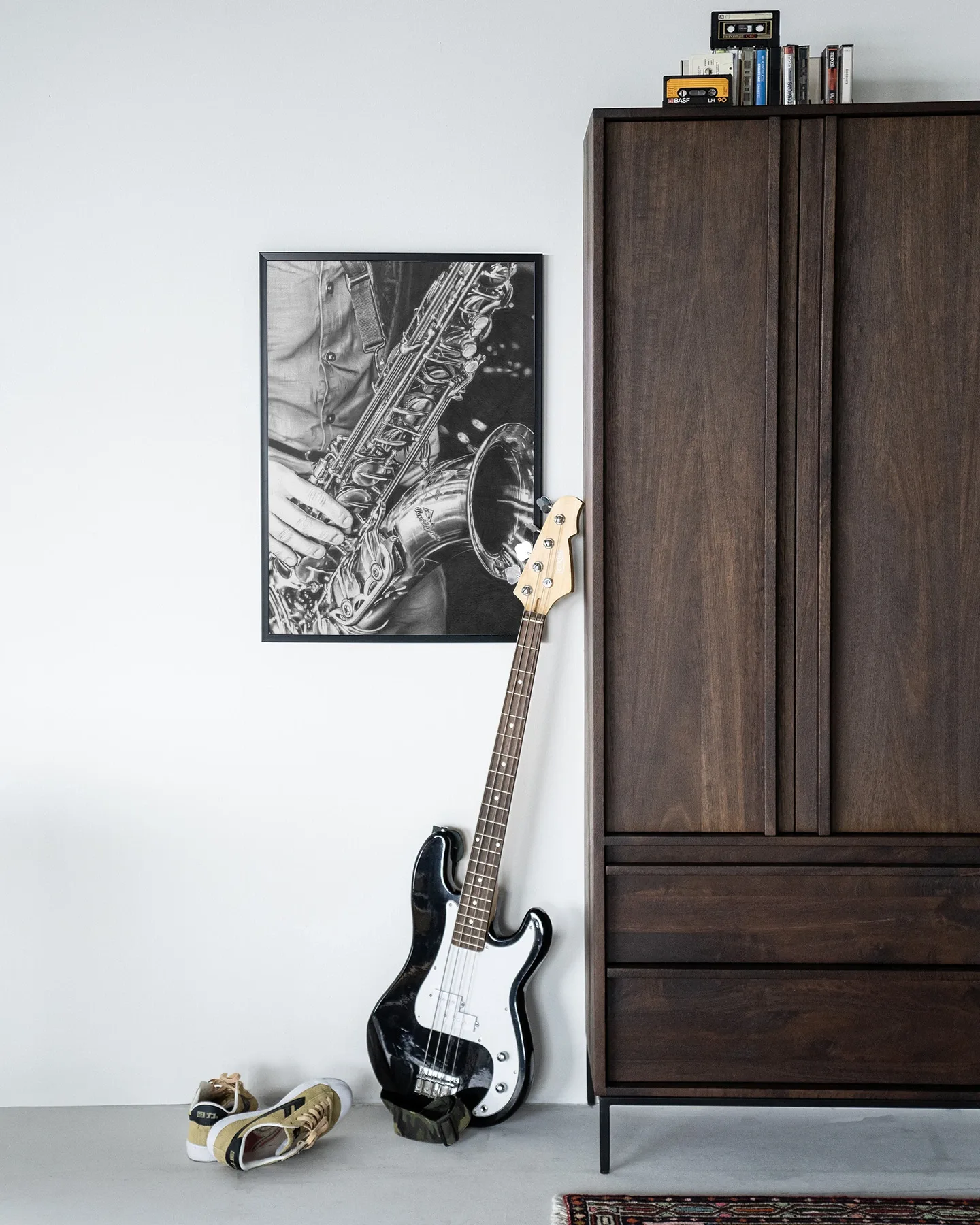Wandkleed The man with the sax - Urban Cotton hangend aan een witte muur, met een basgitaar en schoenen ernaast