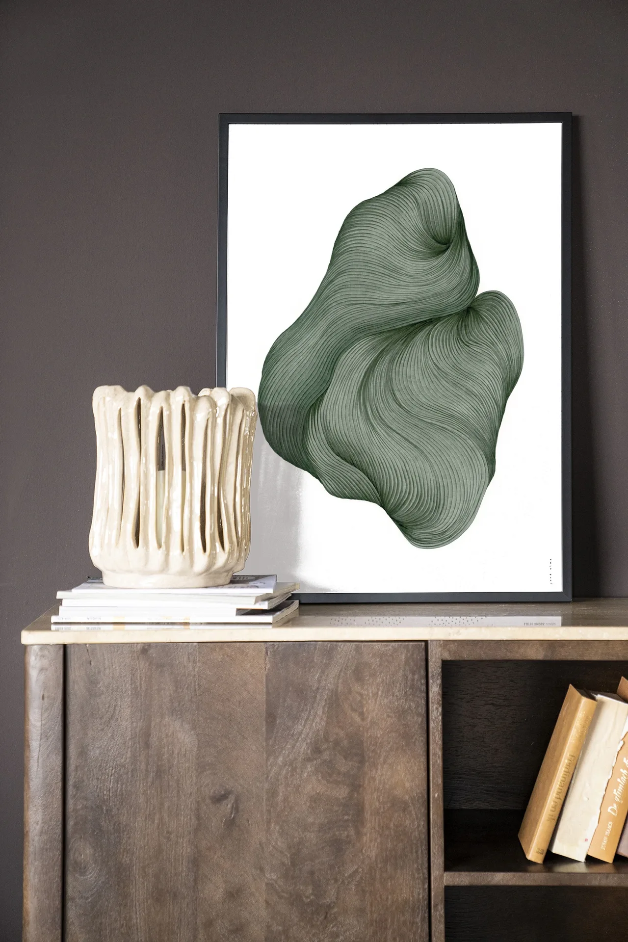 Wandkleed DWG-J - Urban Cotton in een lijst, staand op een houten dressoir met boeken