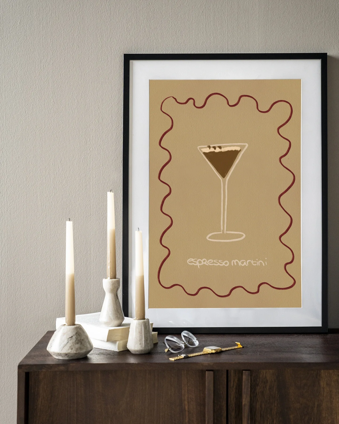 Ein gerahmter Espresso Martini Poster mit drei Kerzen und einer Brille auf einer Holzkommode - Urban Cotton