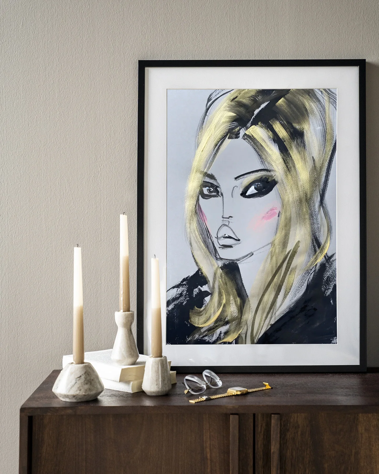 Ein gerahmter Wandteppich Kate Moss - Urban Cotton hängt über einem Holzsideboard mit Kerzen und Büchern