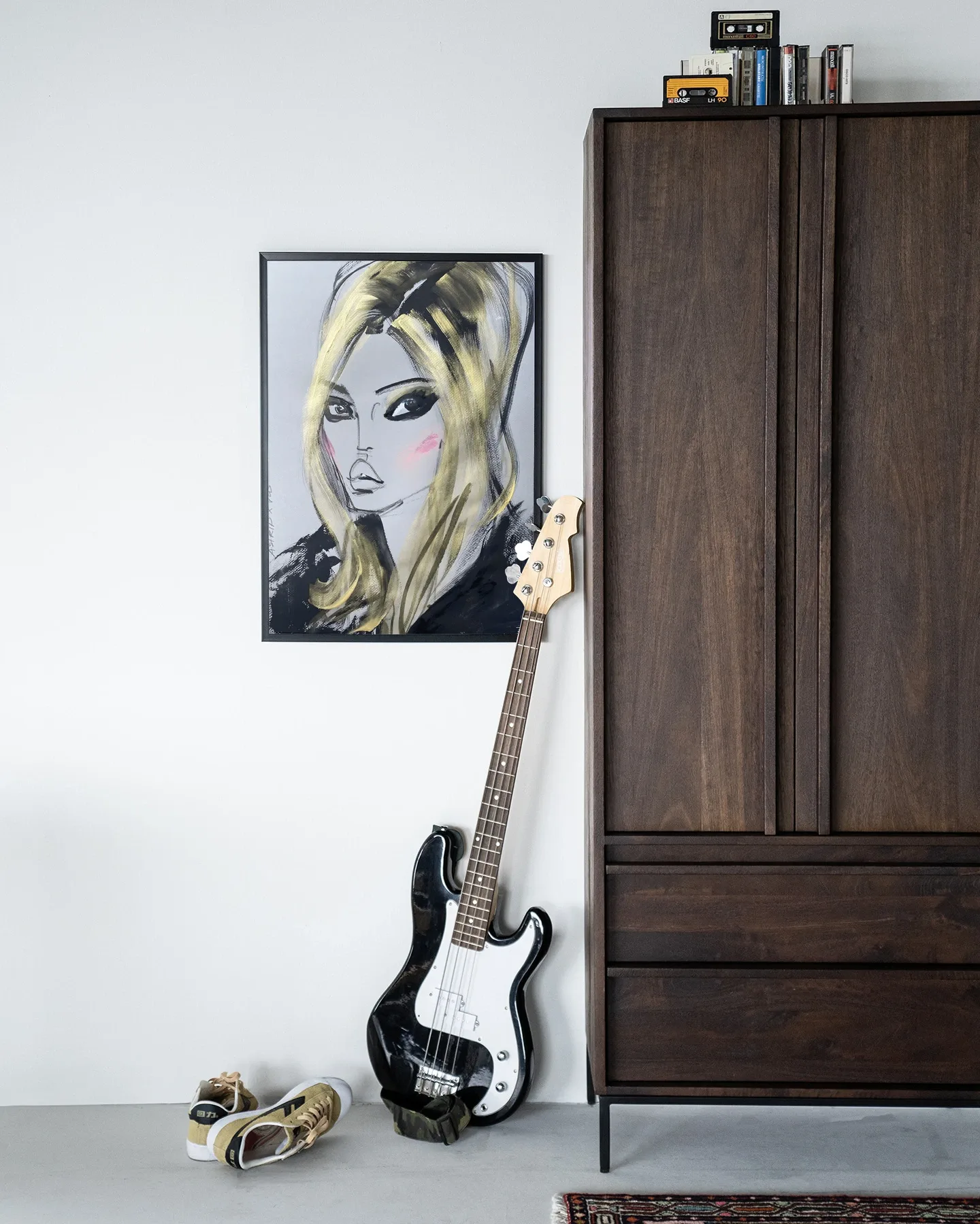 Wandteppich Kate Moss - Urban Cotton hängt an einer weißen Wand, mit einem Bass und Schuhen davor