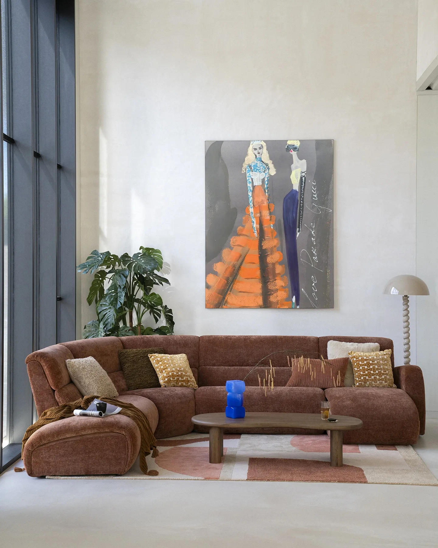Wandbehang Gucci - Urban Cotton hängt über einem braunen Sofa in einem hellen Wohnzimmer