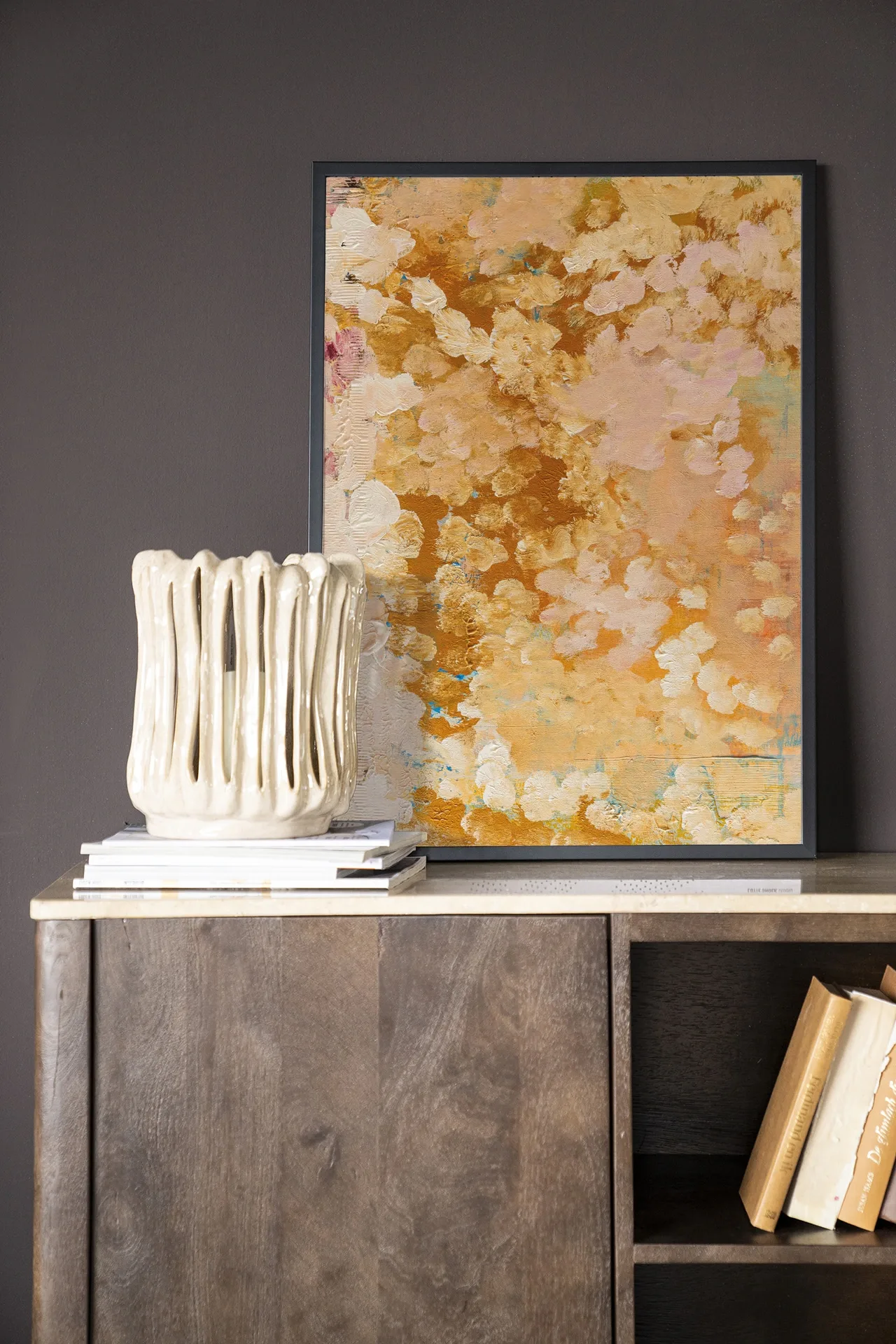 Wandteppich Abundance - Urban Cotton hängt über einem Holzschrank mit einer Vase und Büchern