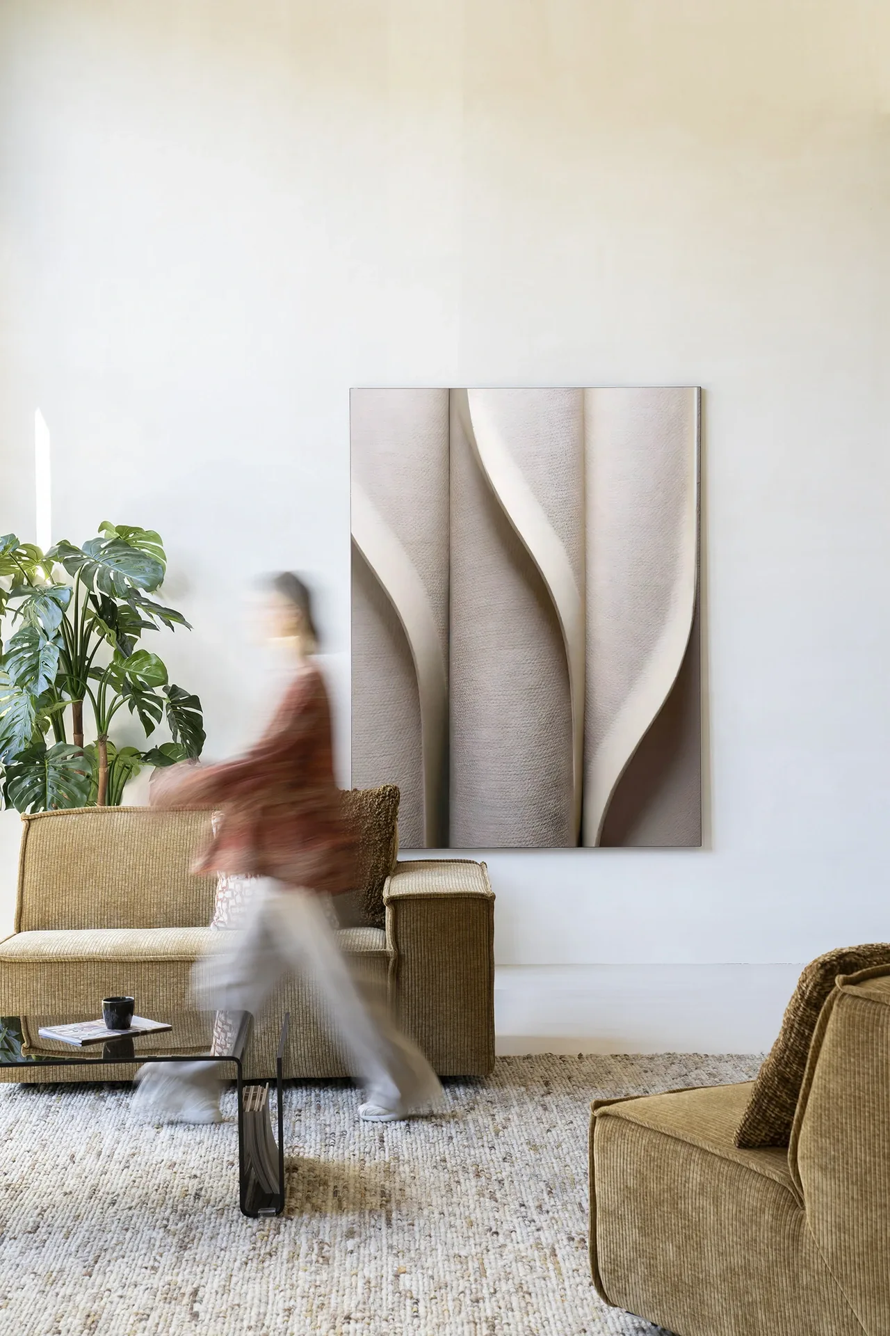 Ein Wandteppich Silent Waves - Urban Cotton hängt an einer weißen Wand in einem Wohnzimmer mit einem Sofa und einem Couchtisch