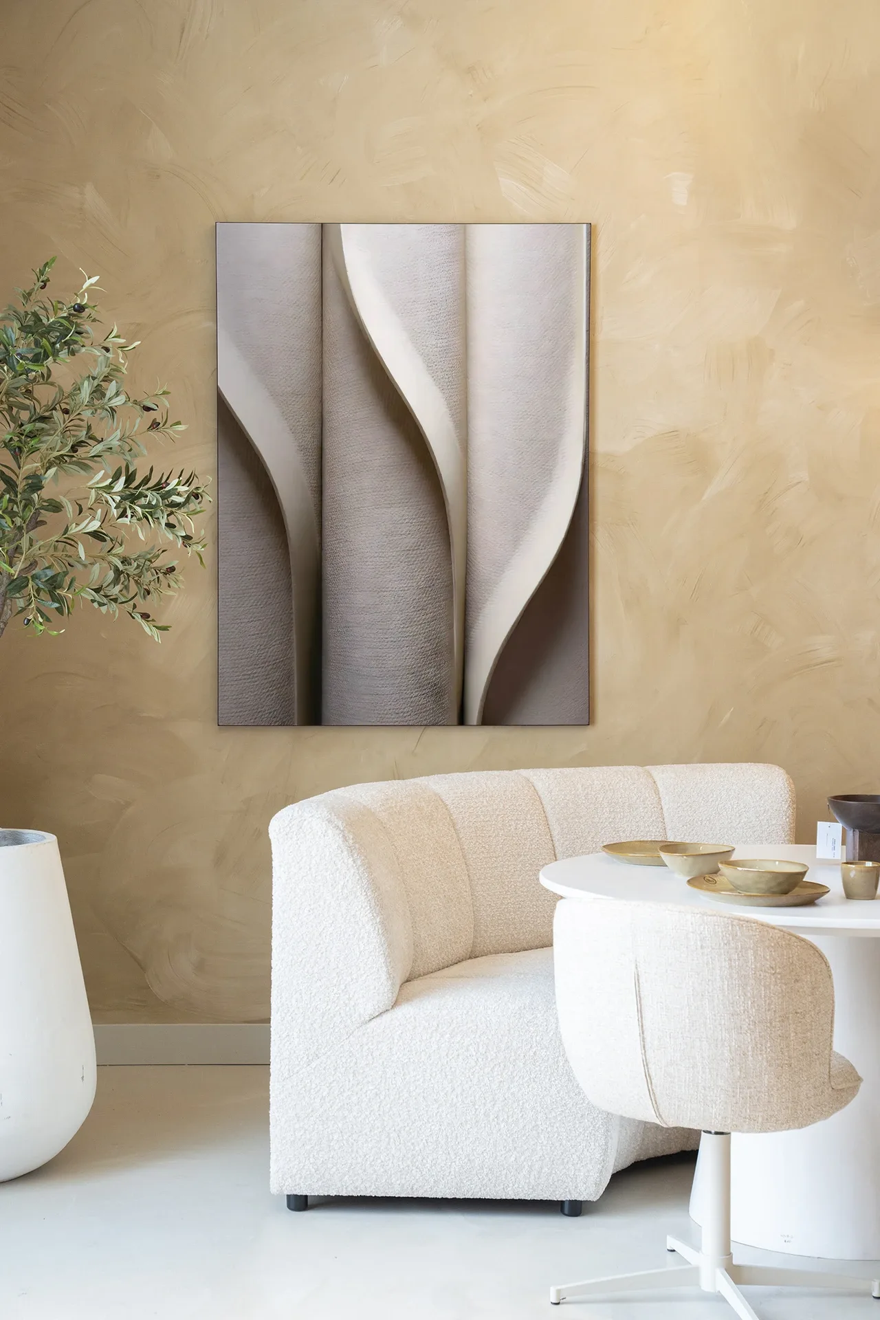 Wandteppich Silent Waves - Urban Cotton hängt an einer beigen Wand über einem cremefarbenen Sofa und einem weißen Tisch mit Schalen