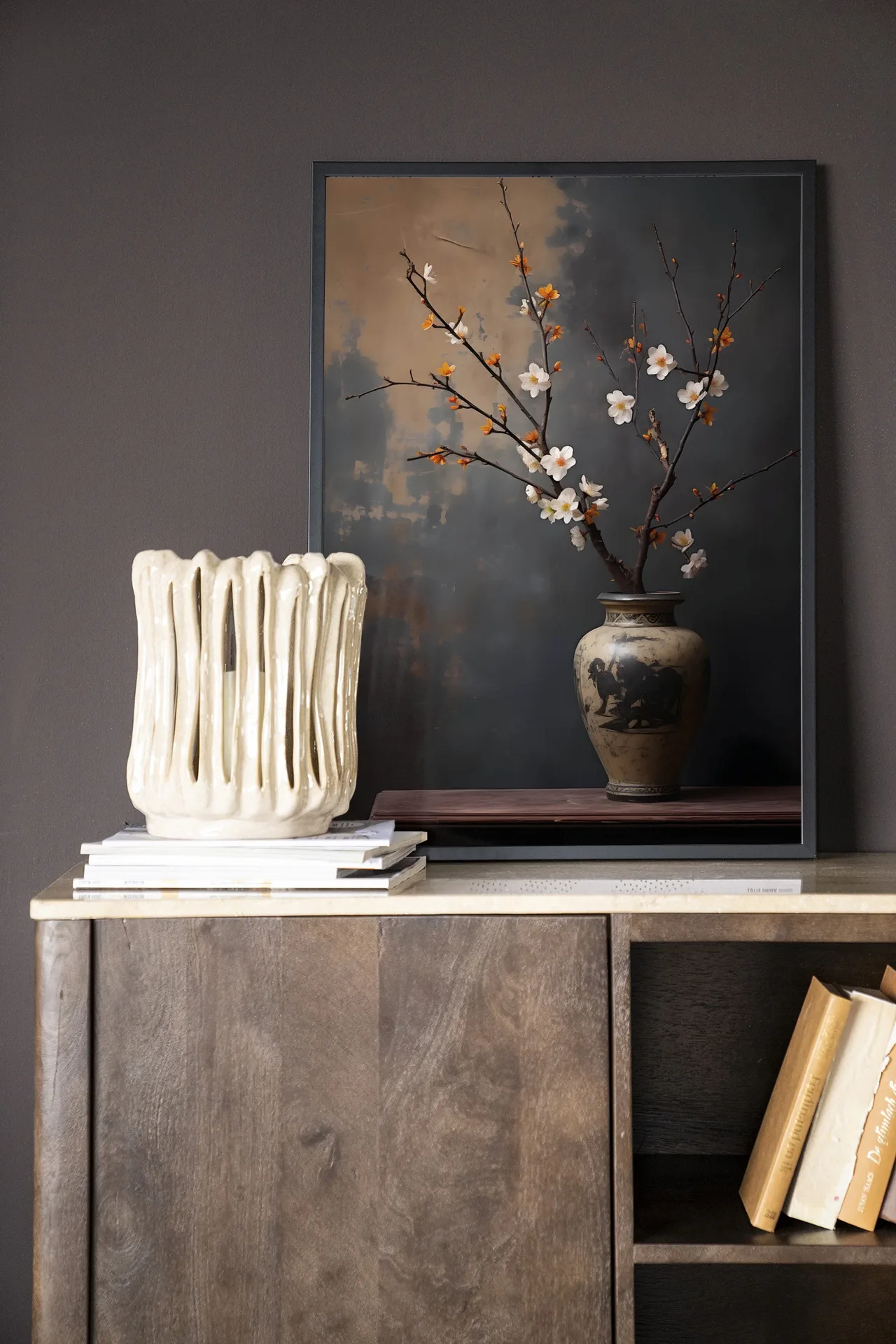 Wandteppich Dark Blossom Vase - Urban Cotton hängt über einem Holzschrank mit einer Vase und Büchern