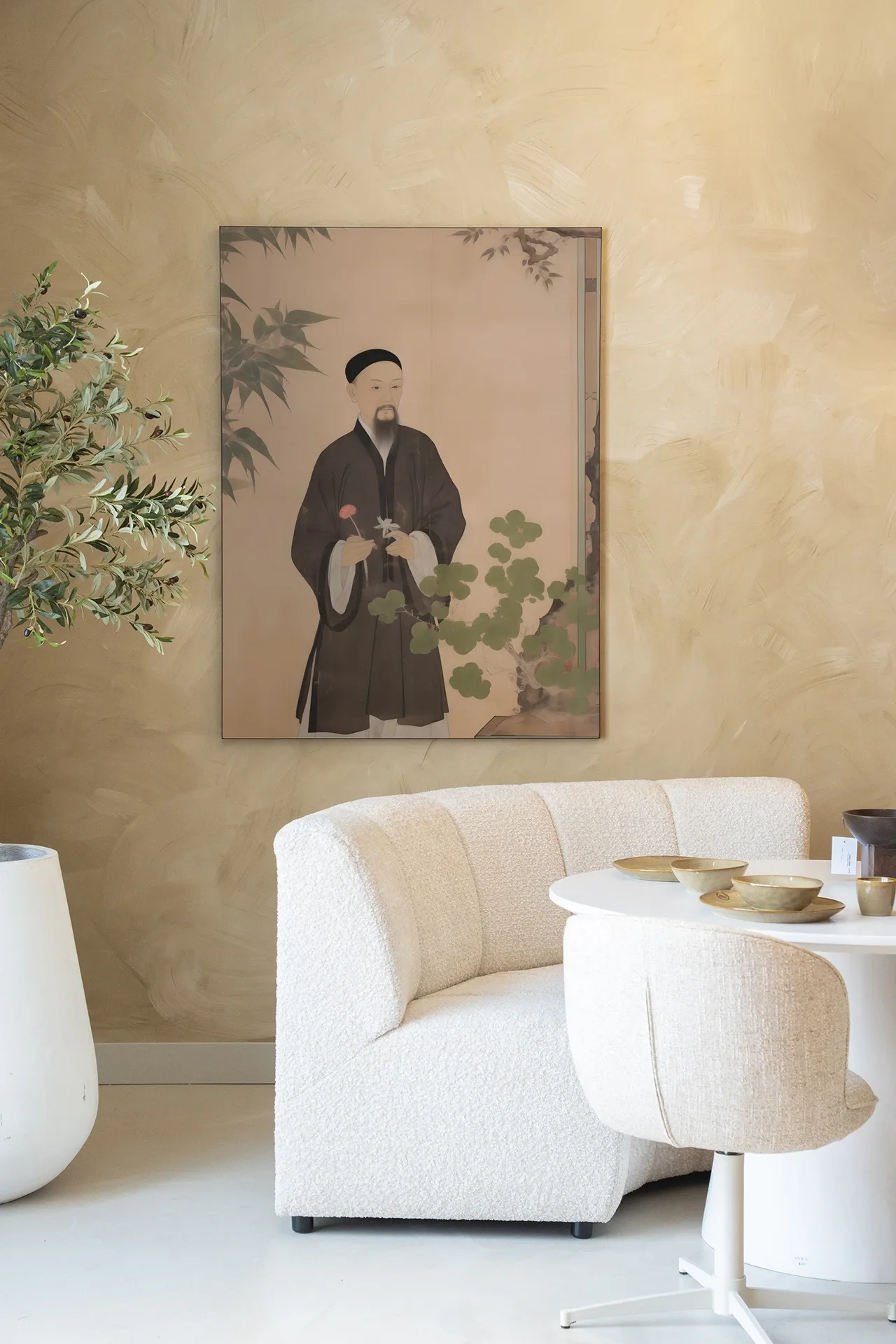 Wandtuch Sakura - Urban Cotton hängt an einer beigefarbenen Wand über einer weißen Bank und einem Tisch