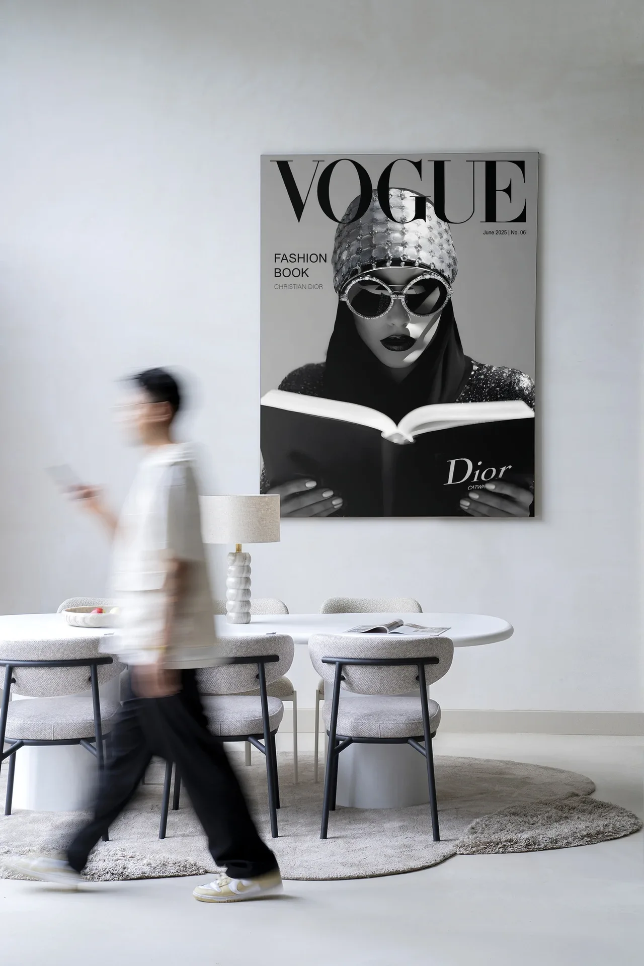 Wandteppich Fashion Book White von Urban Cotton hängt an einer weißen Wand über einem Esstisch mit Stühlen, mit einer vorbeigehenden Person