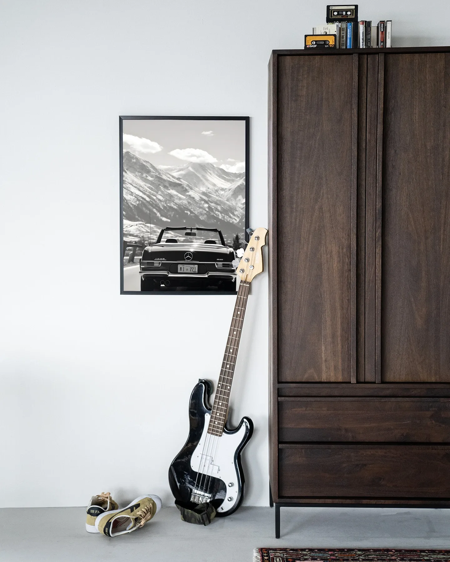 Wandteppich Winter Road - Urban Cotton hängt an einer weißen Wand neben einem dunkelbraunen Schrank, mit einer Bassgitarre und Schuhen auf dem Boden