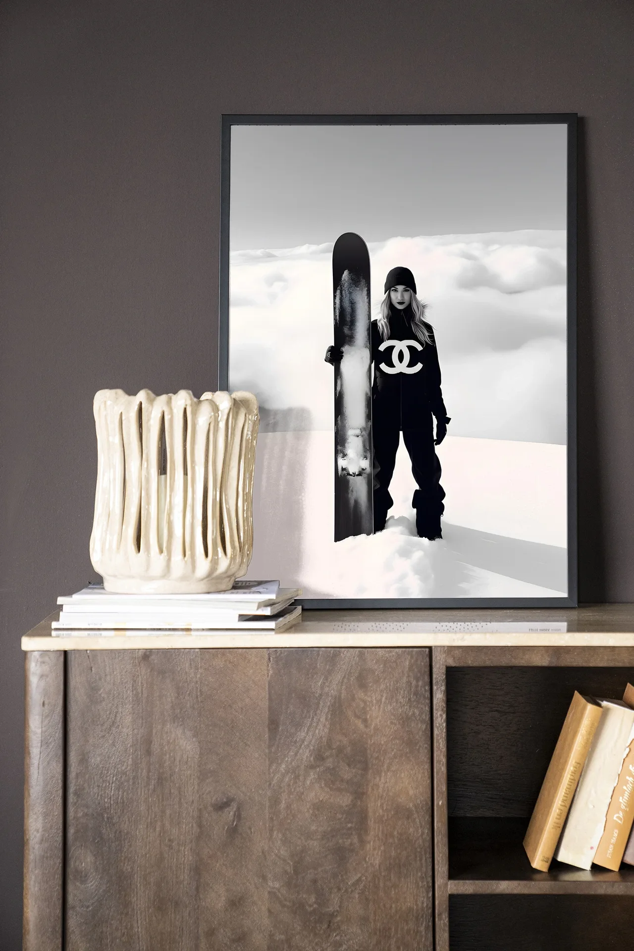 Ein gerahmter Wandteppich Snow Girl - Urban Cotton steht auf einem Holzbuffet mit einer Vase und Büchern