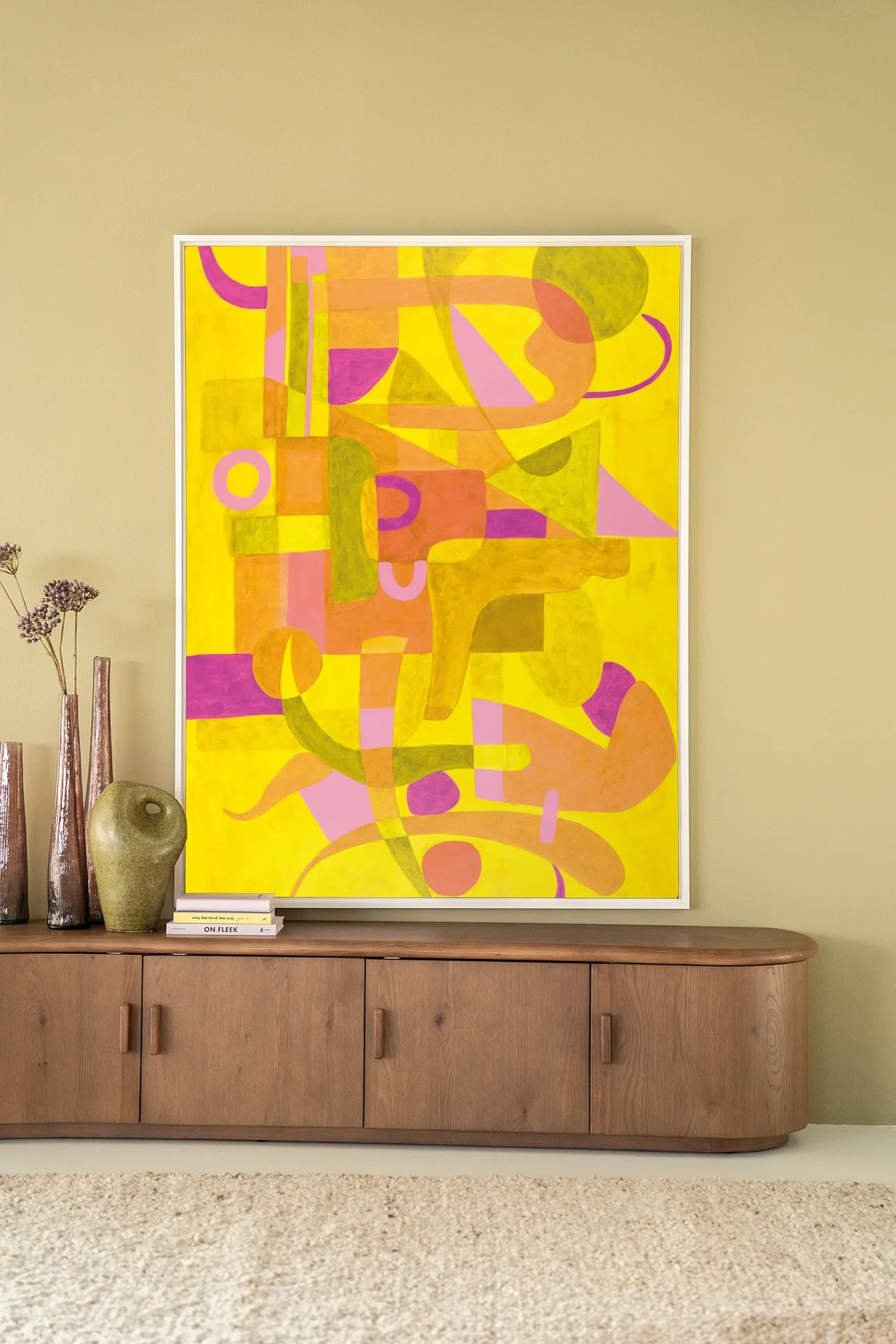 Wandteppich Otono Dorado - Urban Cotton hängt über einem Holzsideboard mit Vasen und Büchern