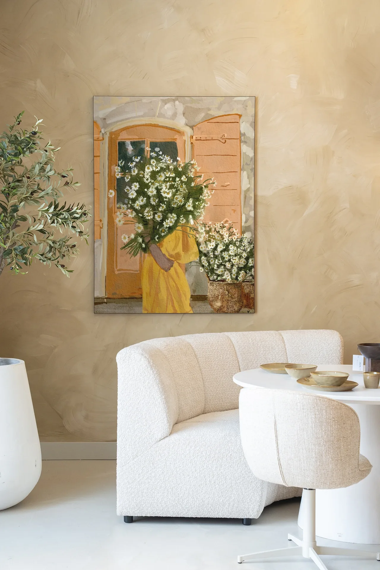 Wandteppich Daisy Lady - Urban Cotton hängt an einer beigen Wand über einem weißen Sofa und Tisch