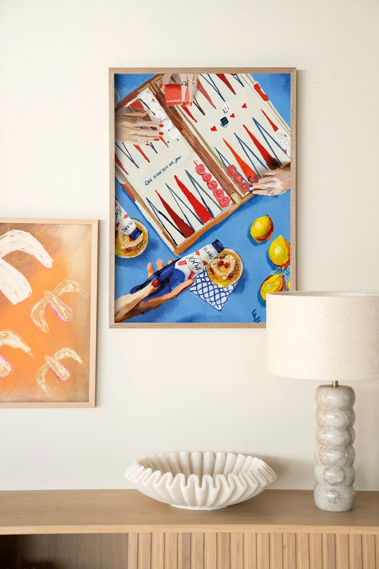 Ein gerahmter Wandteppich It's Not A Game - Urban Cotton hängt an einer hellen Wand über einem Sideboard aus Holz