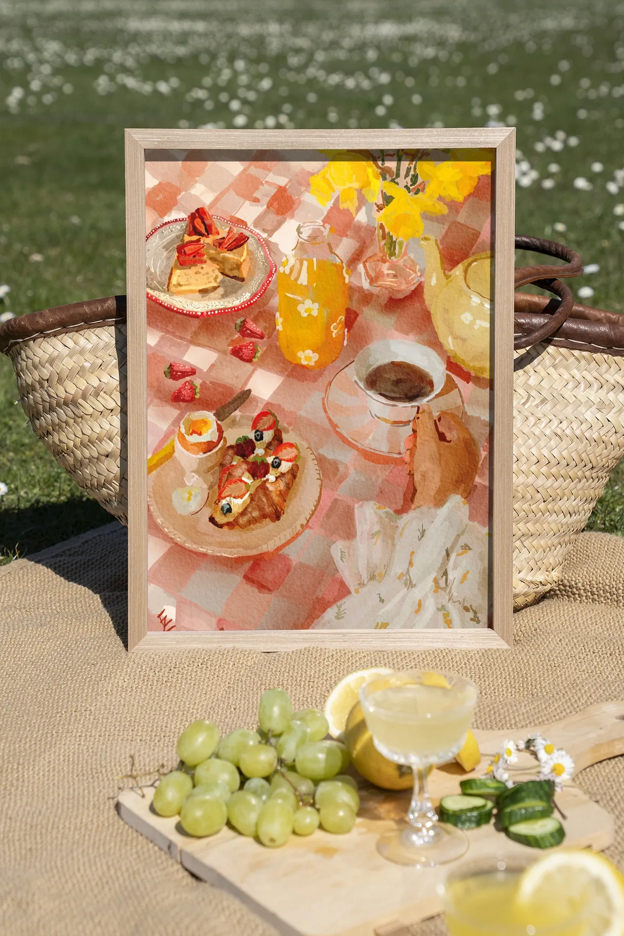 Wandteppich Spring Breakfast - Urban Cotton in einem hellen Holzrahmen, auf einer Picknickdecke im Gras stehend