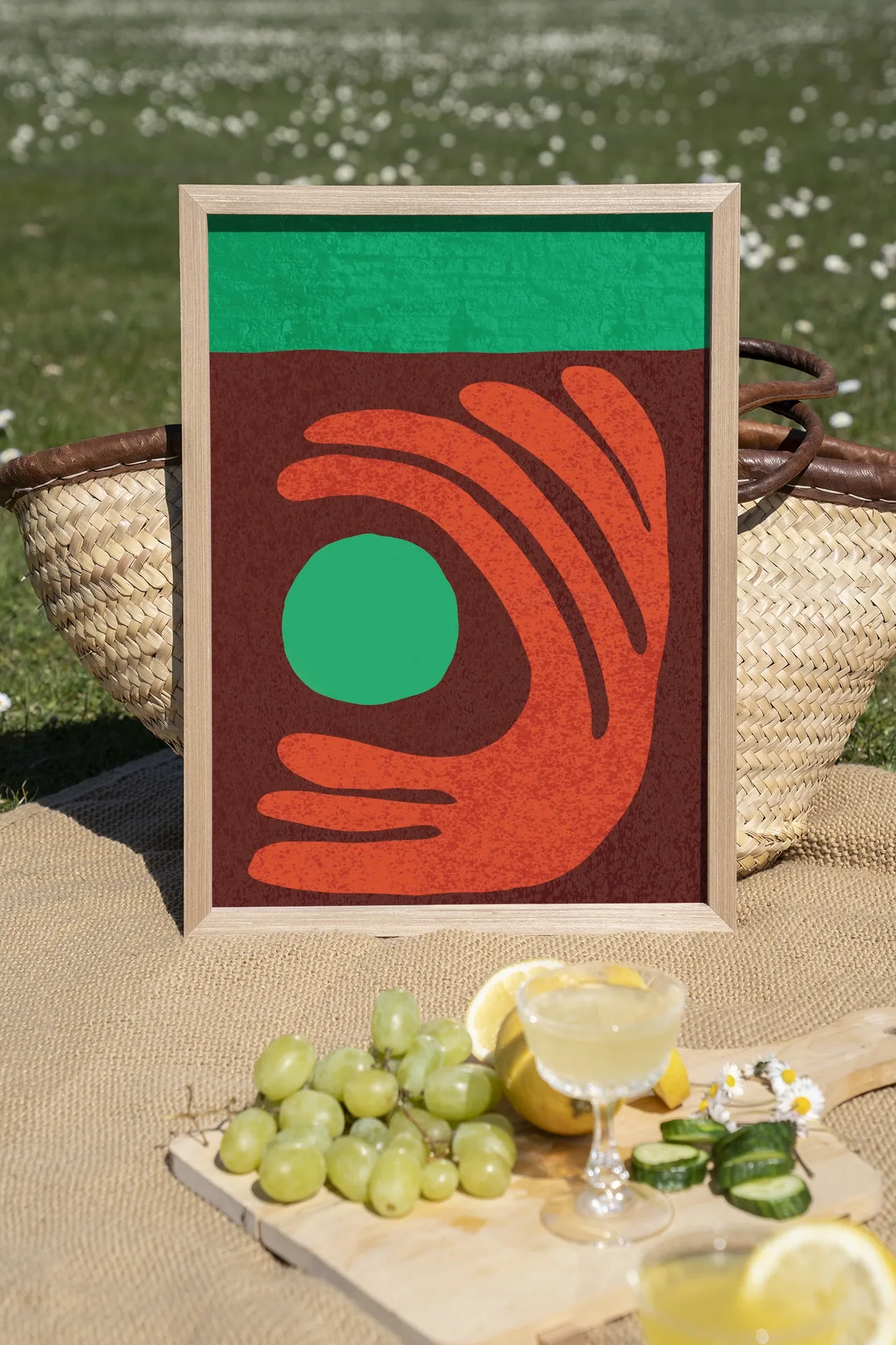 Wandteppich Elements Green in einem Holzrahmen, stehend auf einer Picknickdecke mit Obst und Getränken - Urban Cotton