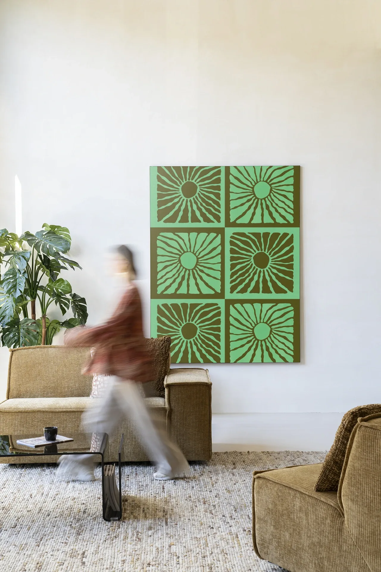 Wandteppich Suns In Green - Urban Cotton in einem hellen Wohnzimmer mit einer vorbeigehenden Person