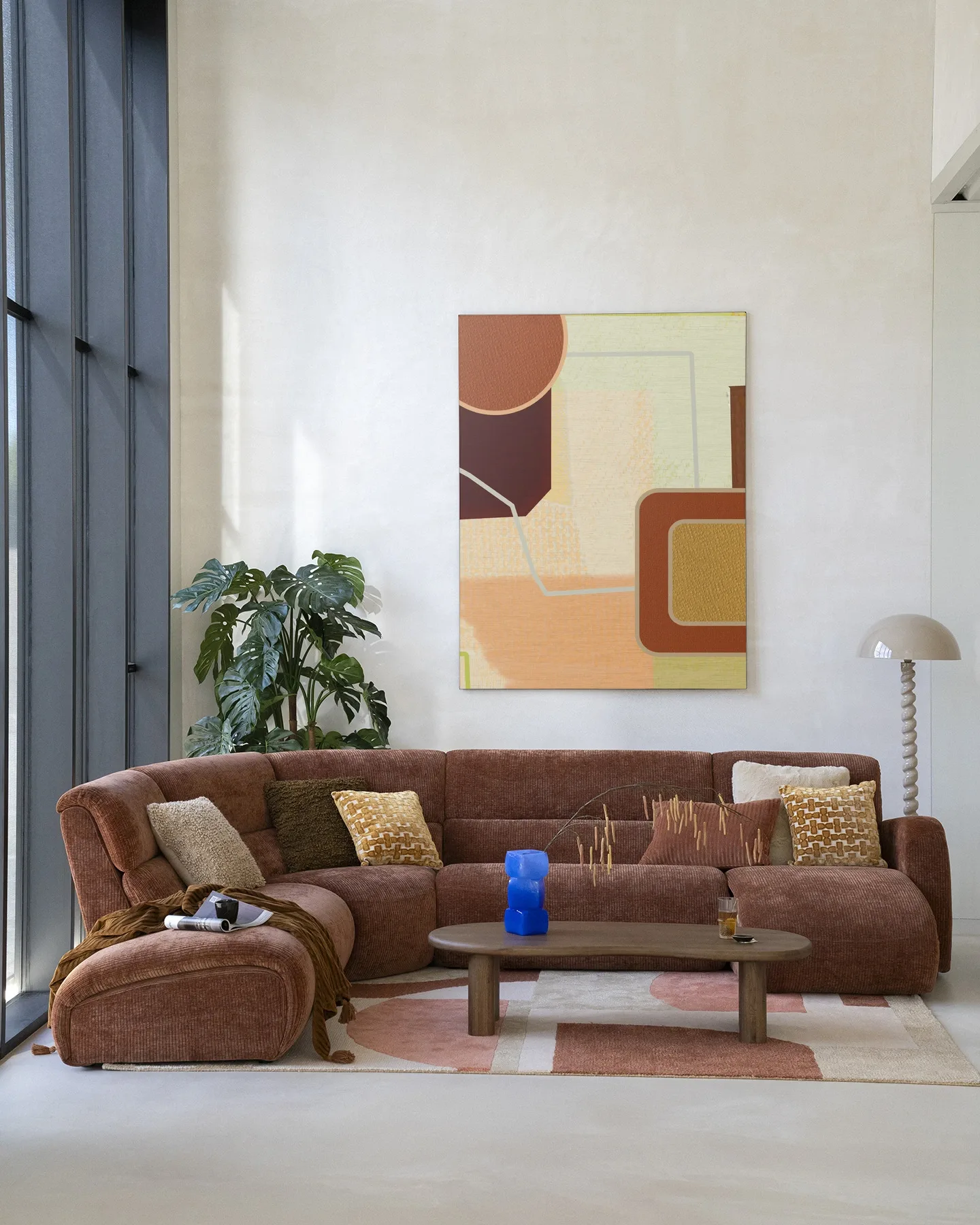 Wandteppich Deuce - Urban Cotton hängt über einem braunen Ecksofa in einem hellen Wohnzimmer