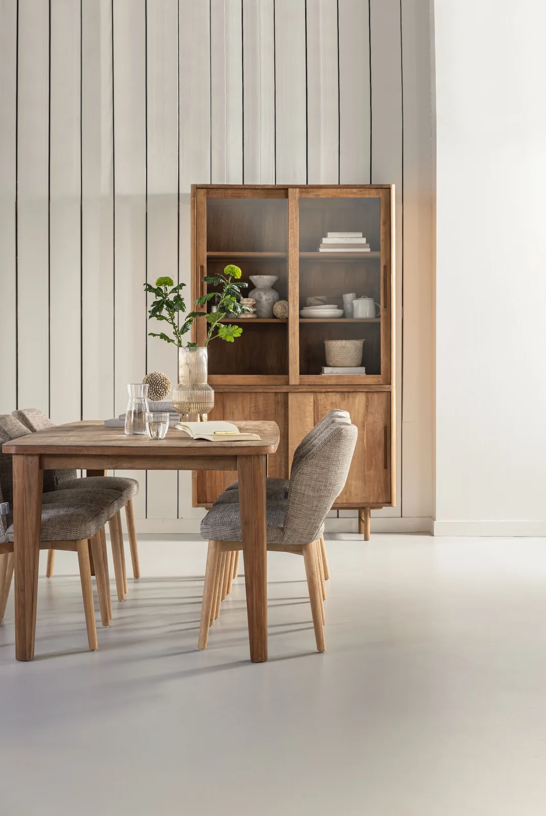 De Vitrinekast Bliss medium in een lichte studio-setting met een eettafel en stoelen op de voorgrond - DTP Home