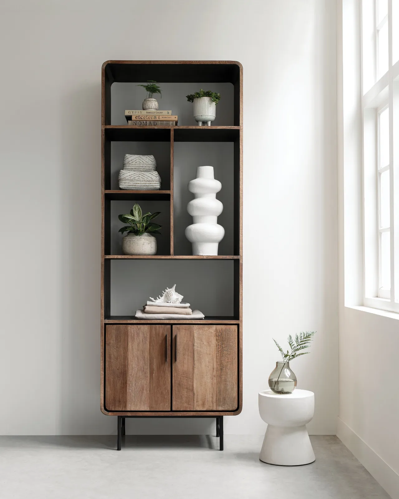 Boekenkast Evo in een lichte studio met decoratie en planten, vanuit een recht camerastandpunt - DTP Home