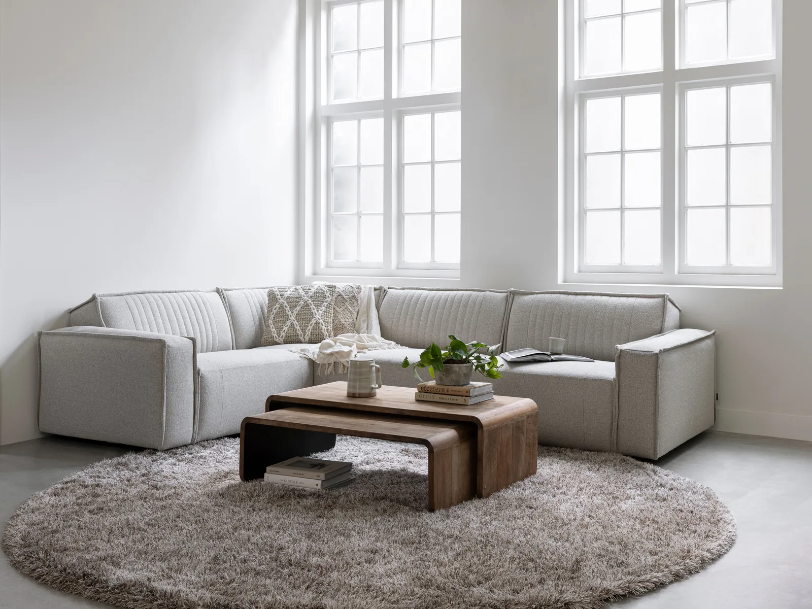 Der Couchtisch Evo in einem hellen Wohnzimmer mit einem grauen Ecksofa und rundem Teppich - DTP Home