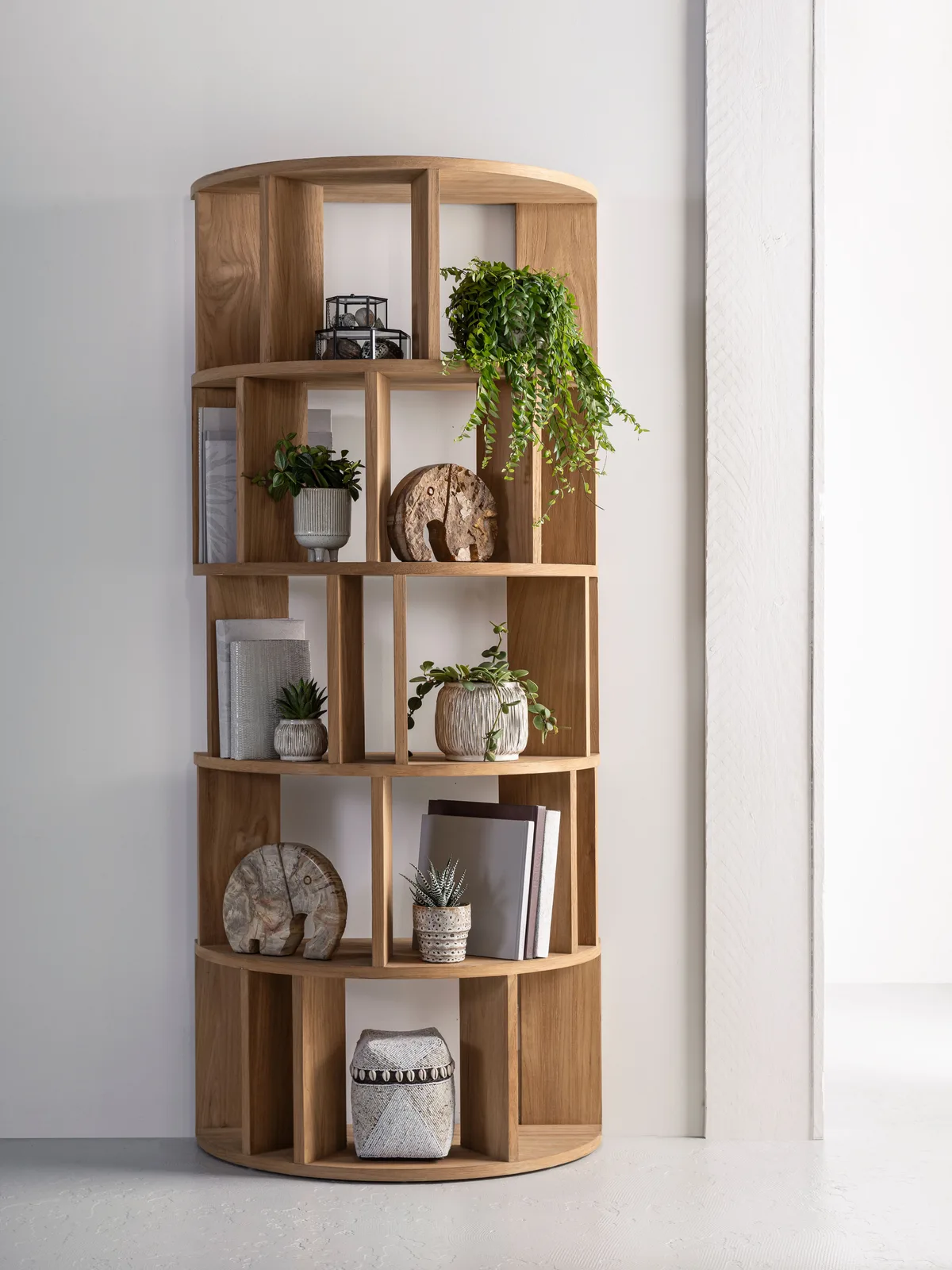 De Boekenkast Forte rond in een studio met witte muren, gevuld met planten en decoratie - DTP Home