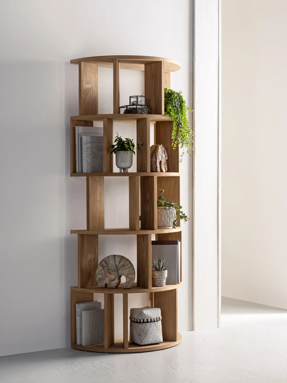 Boekenkast Forte rond in een lichte interieurstudio, gevuld met boeken en planten - DTP Home