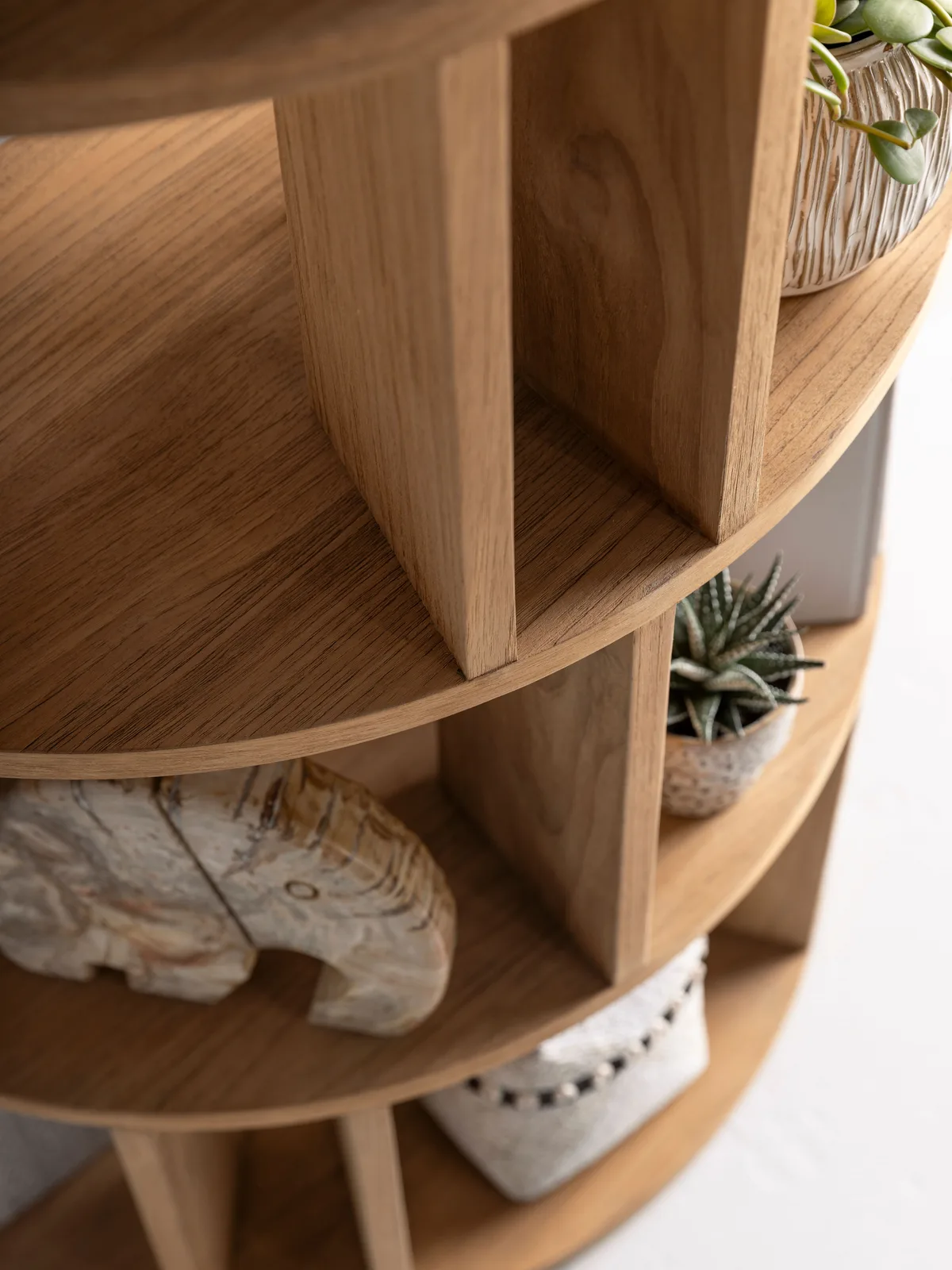 Detailopname van de ronde Boekenkast Forte, met verschillende vakken en decoratie zoals planten en een olifantbeeldje - DTP Home