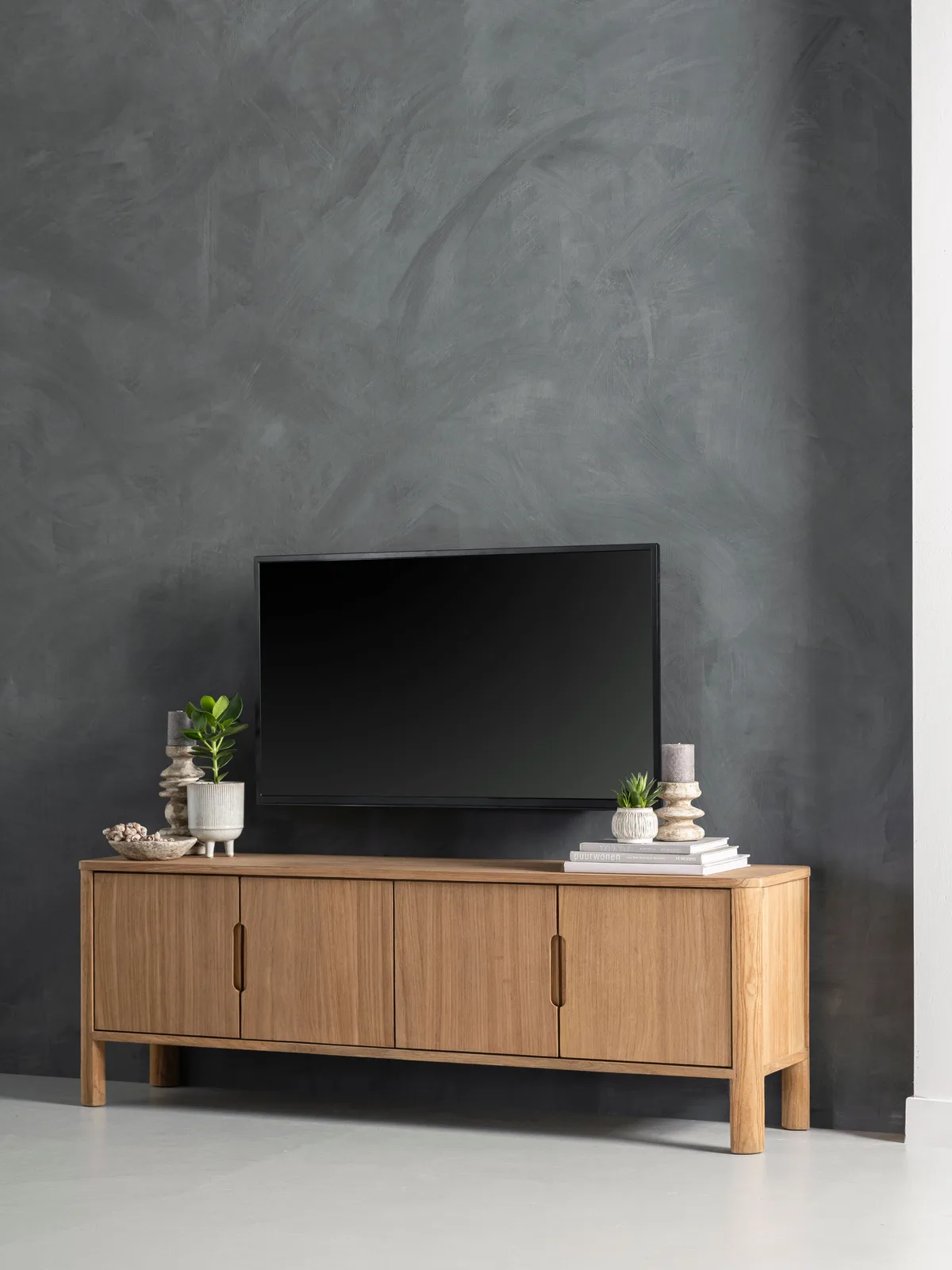 Tv-meubel Forte in een moderne studio met een donkergrijze, gestuukte muur en een tv erop - DTP Home