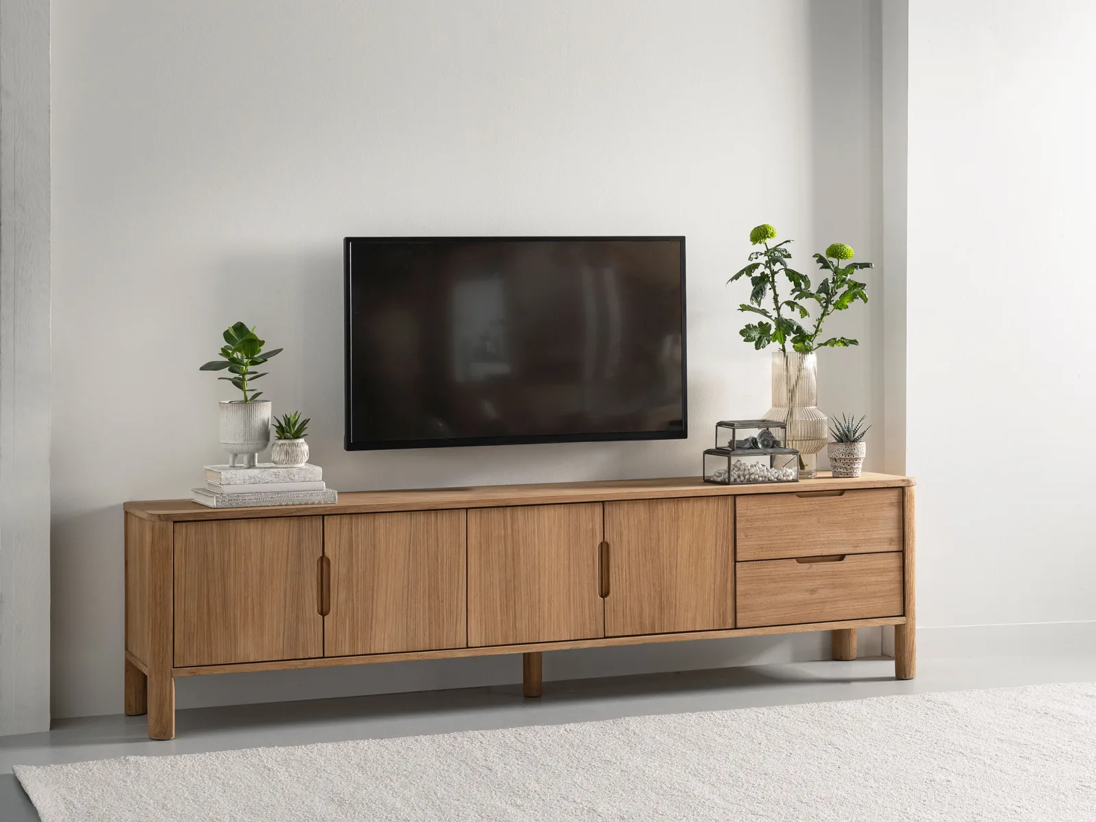 Tv-meubel Forte in een lichte woonkamer met een tv erboven en decoratie erop - DTP Home