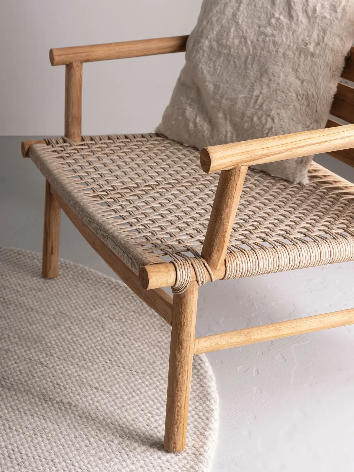 Loungesessel Ono mit einem hellen Kissen darauf, stehend auf einem runden Teppich - MUST Living