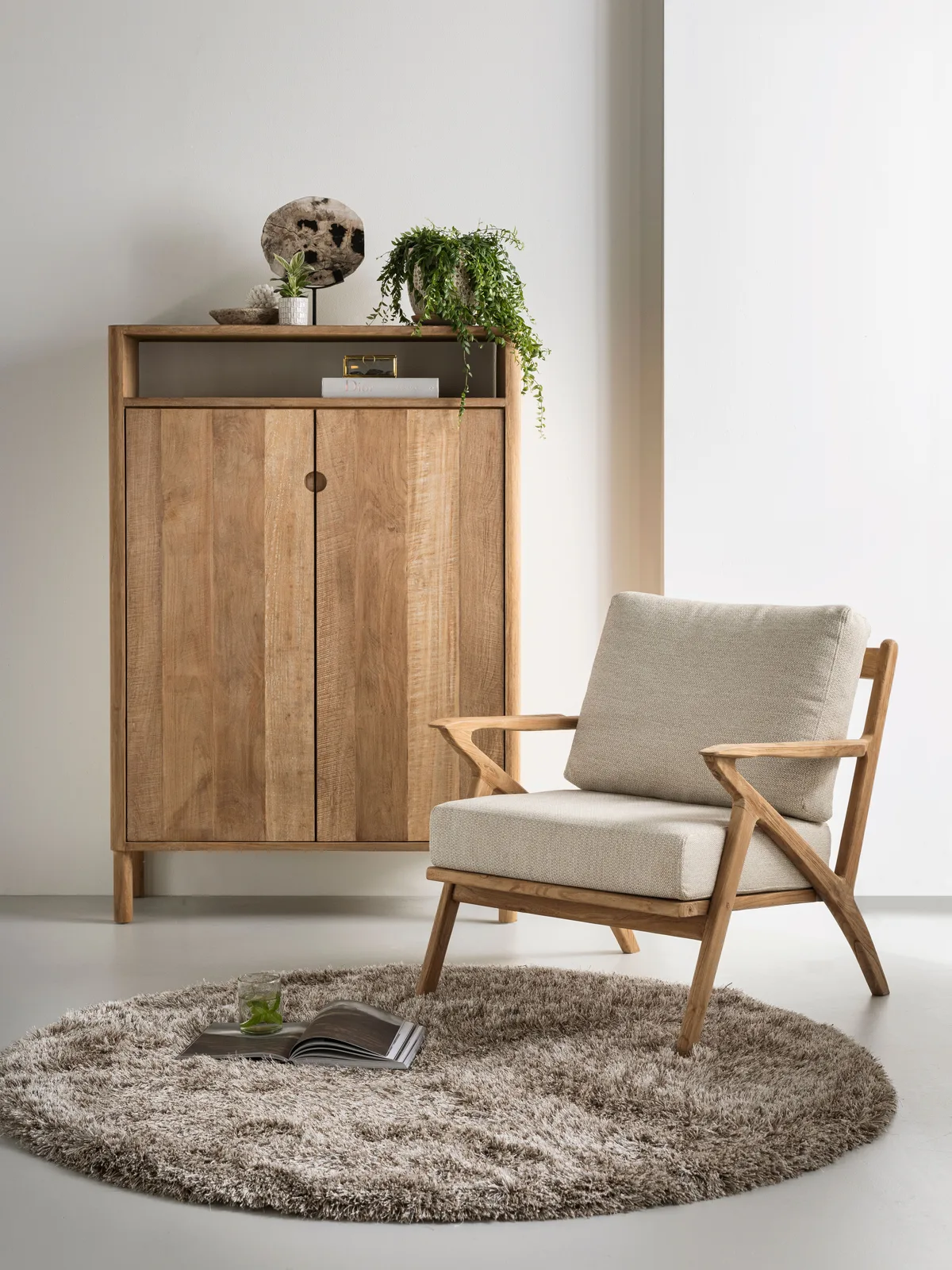Loungesessel Charles in einem hellen Studio mit einem Holzschrank und einem runden Teppich - MUST Living