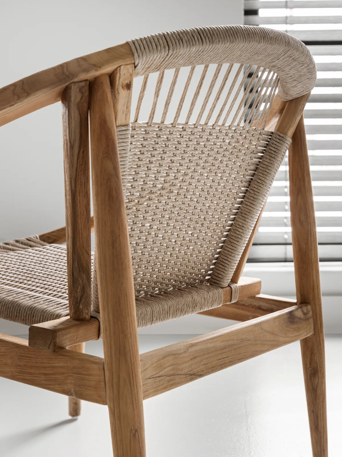 Detail des Loungesessels Kumo, mit der geflochtenen Rückenlehne und dem Holzrahmen aus schräger Perspektive - MUST Living