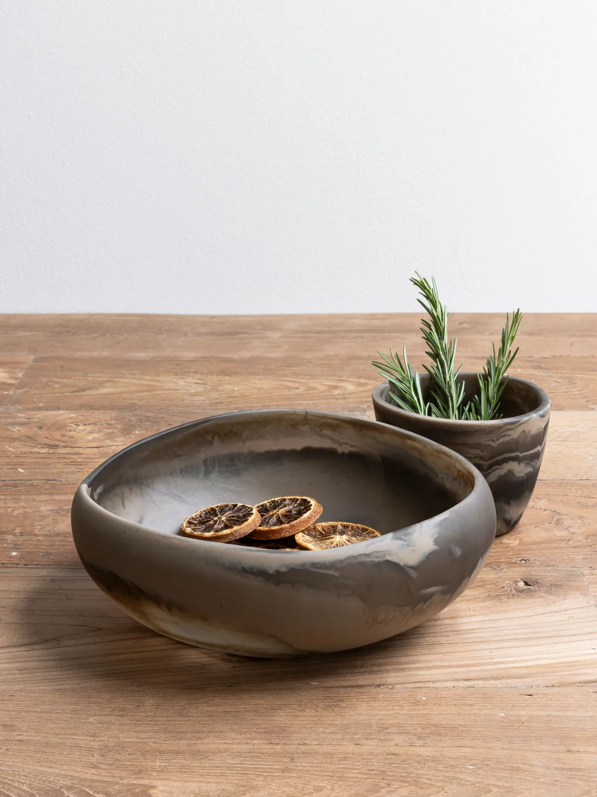 Dienblad Bowl Donatello 2 met gedroogde sinaasappelschijfjes en een kleiner potje met rozemarijn op houten ondergrond - MUST Living