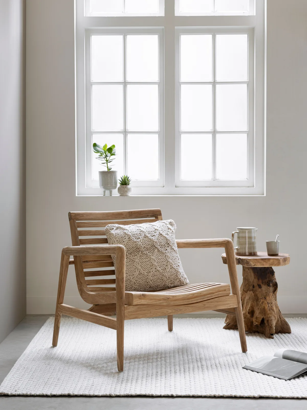 Loungestoel Ray mit einem Kissen in einem hellen Wohnzimmer mit einem Fenster und Pflanzen - MUST Living