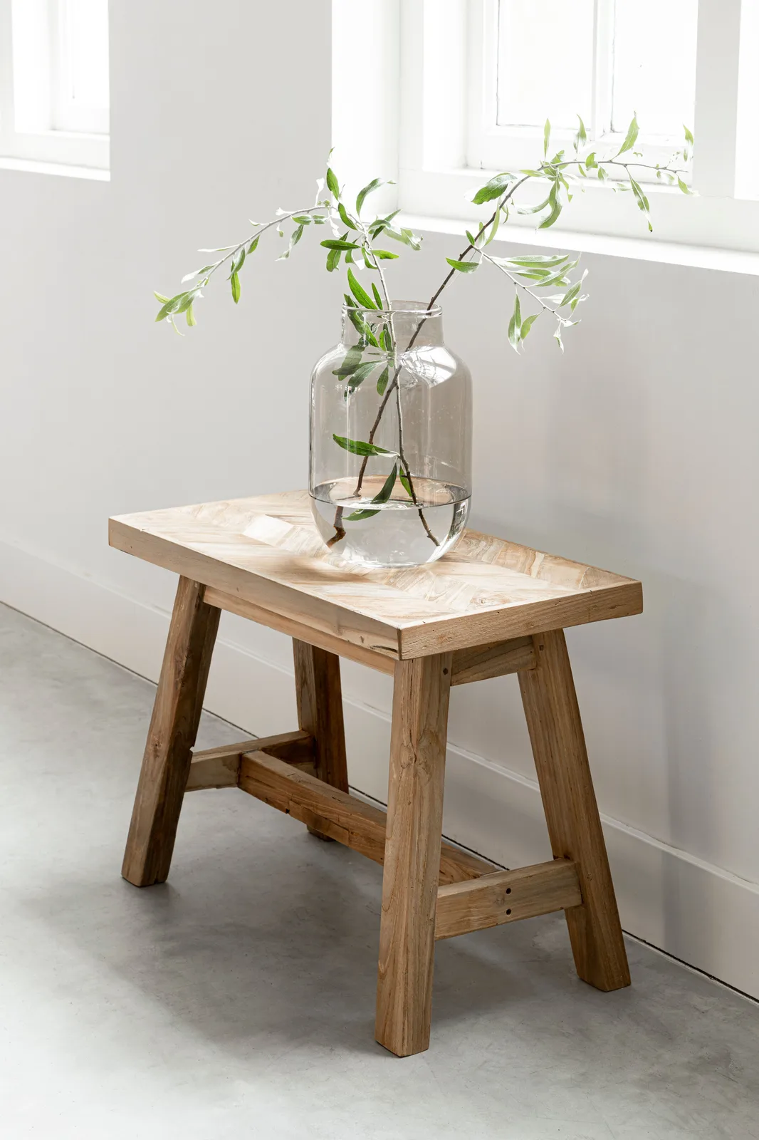 Essbank Herringbone small in einem Studio mit weißen Wänden und einer Vase mit Zweigen - MUST Living