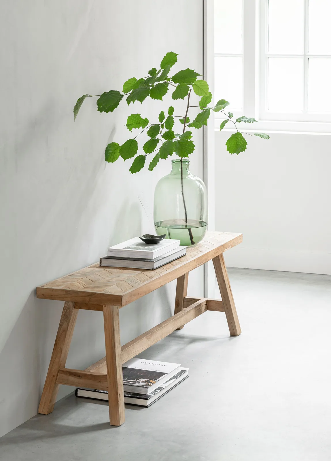 Essbank Herringbone small mit Dekoration aus Büchern und einer Vase mit Ästen in einem hellen Raum - MUST Living